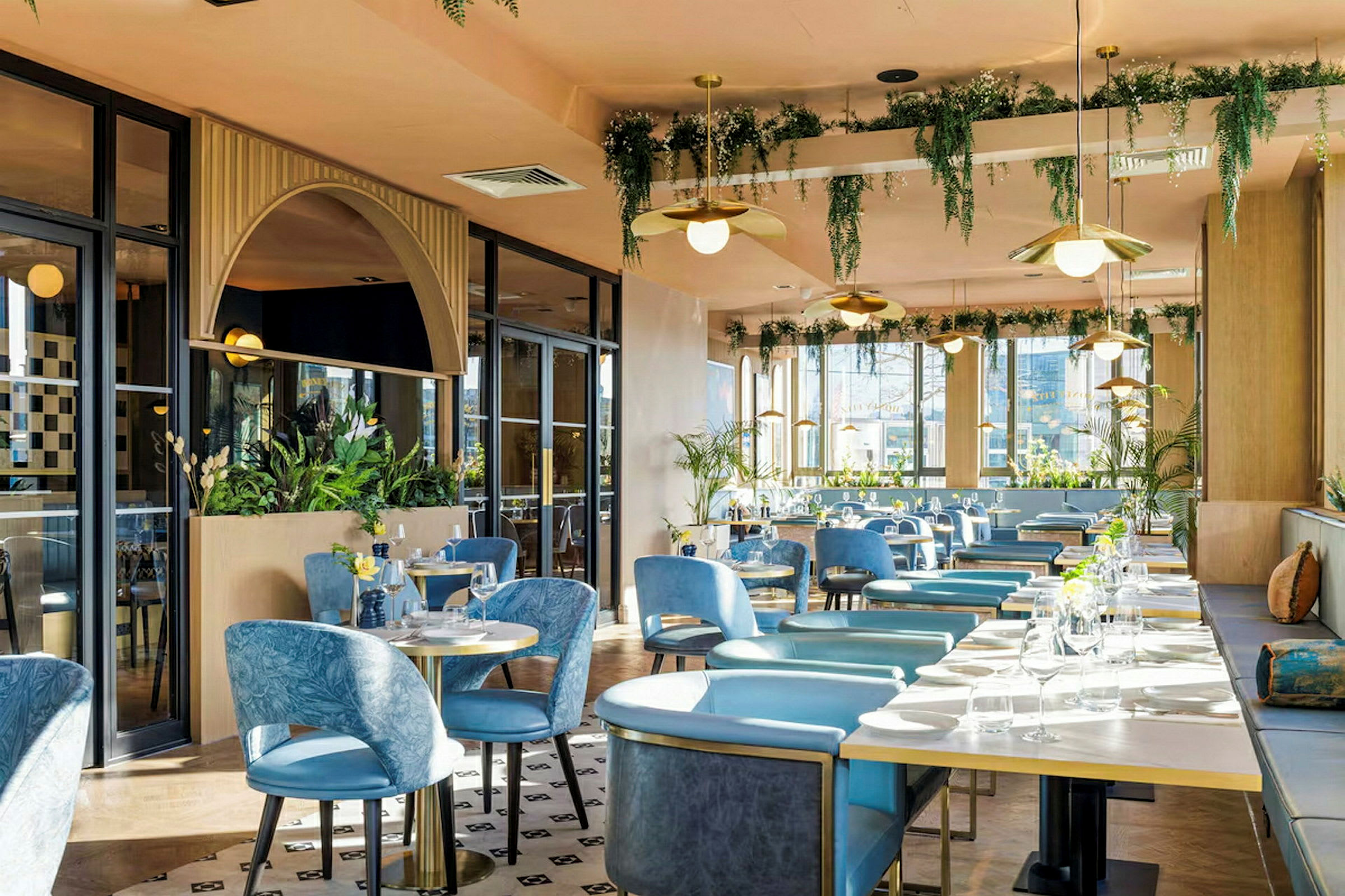 En restaurant med blå stole, borde og planteudsmykninger. (AI-genereret tekst)