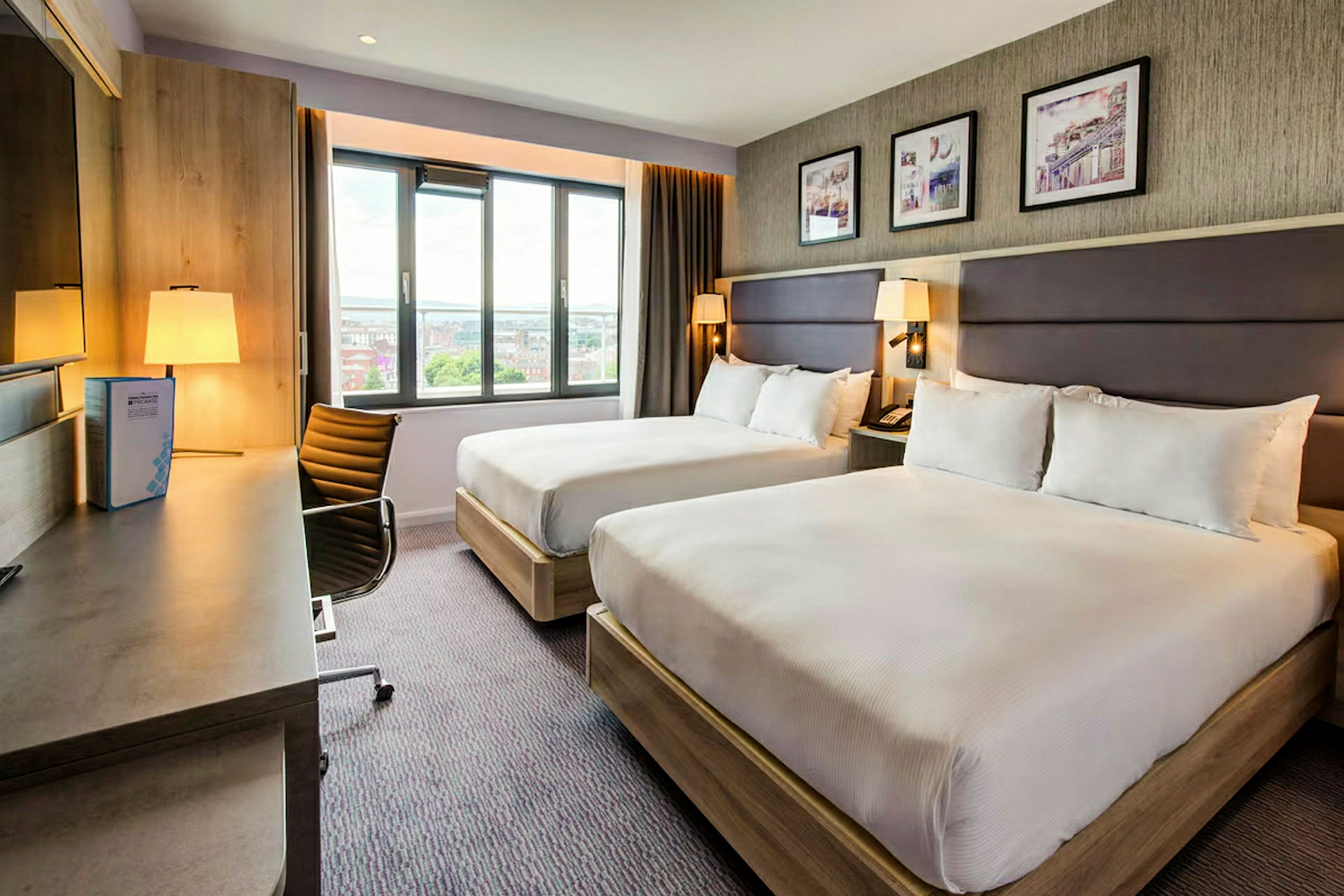 Hotelværelse med to senge, skrivebord og vindue. (AI-genereret tekst)