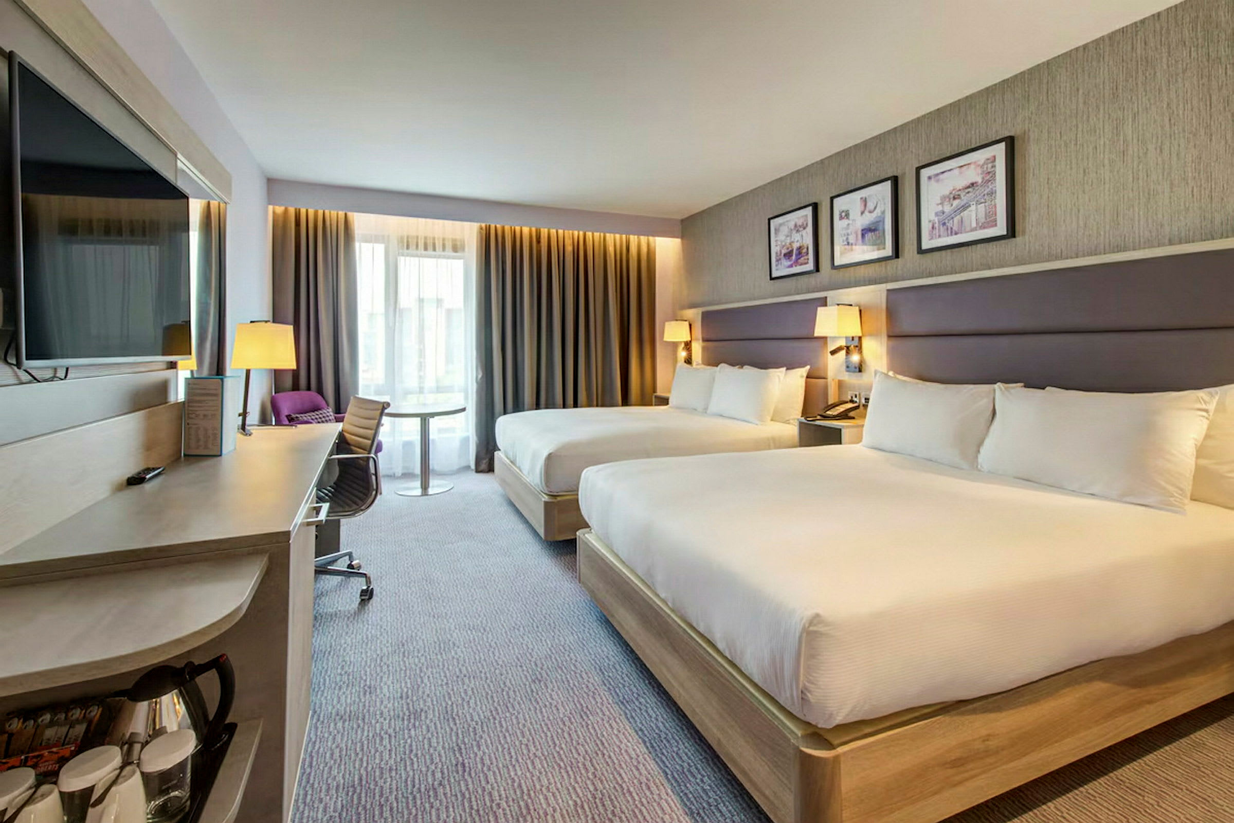 Hotelværelse med to brede senge, skrivebord og moderne indretning. (AI-genereret tekst)
