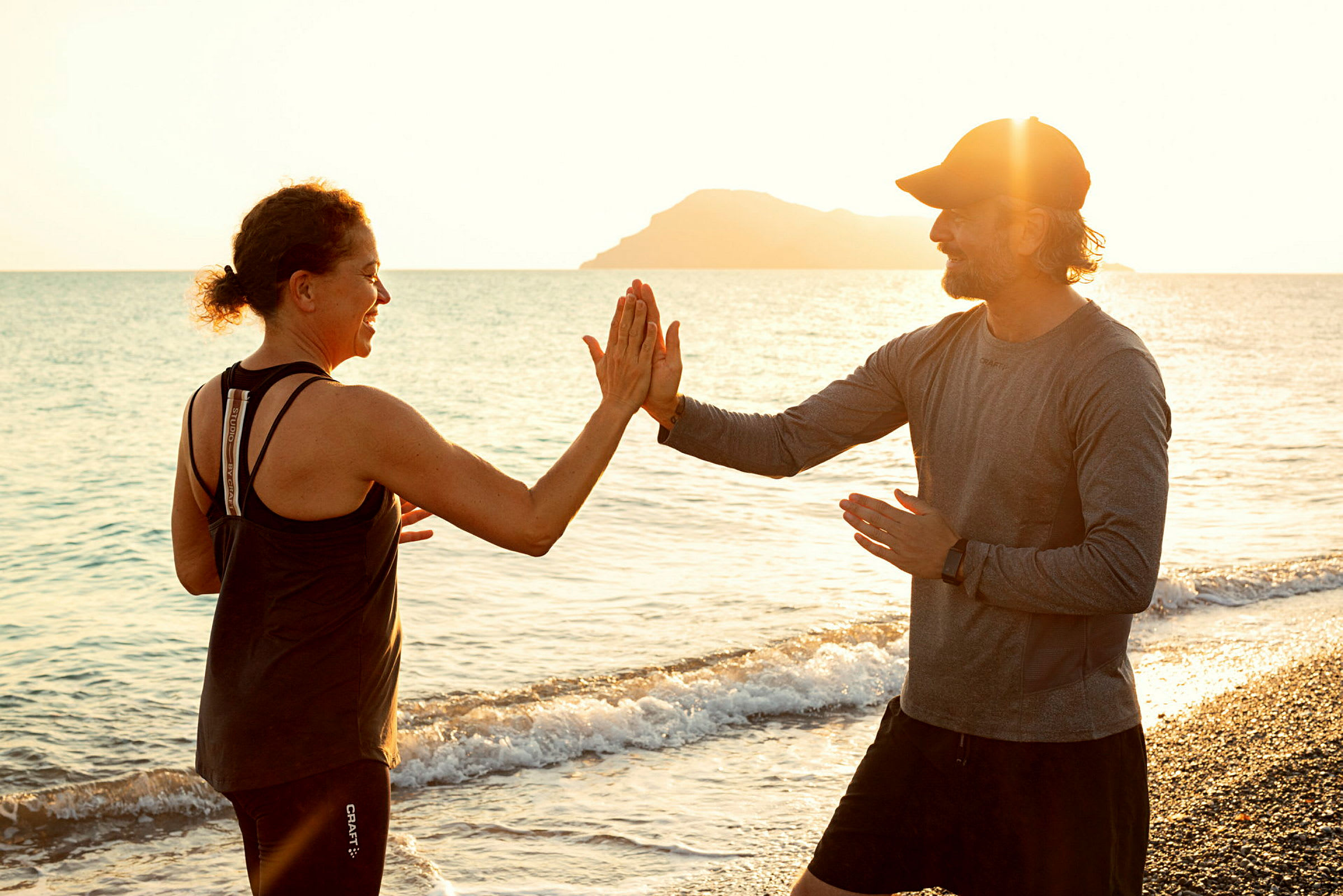 To personer træner ved en strand med solnedgang i baggrunden. (AI-genereret tekst)