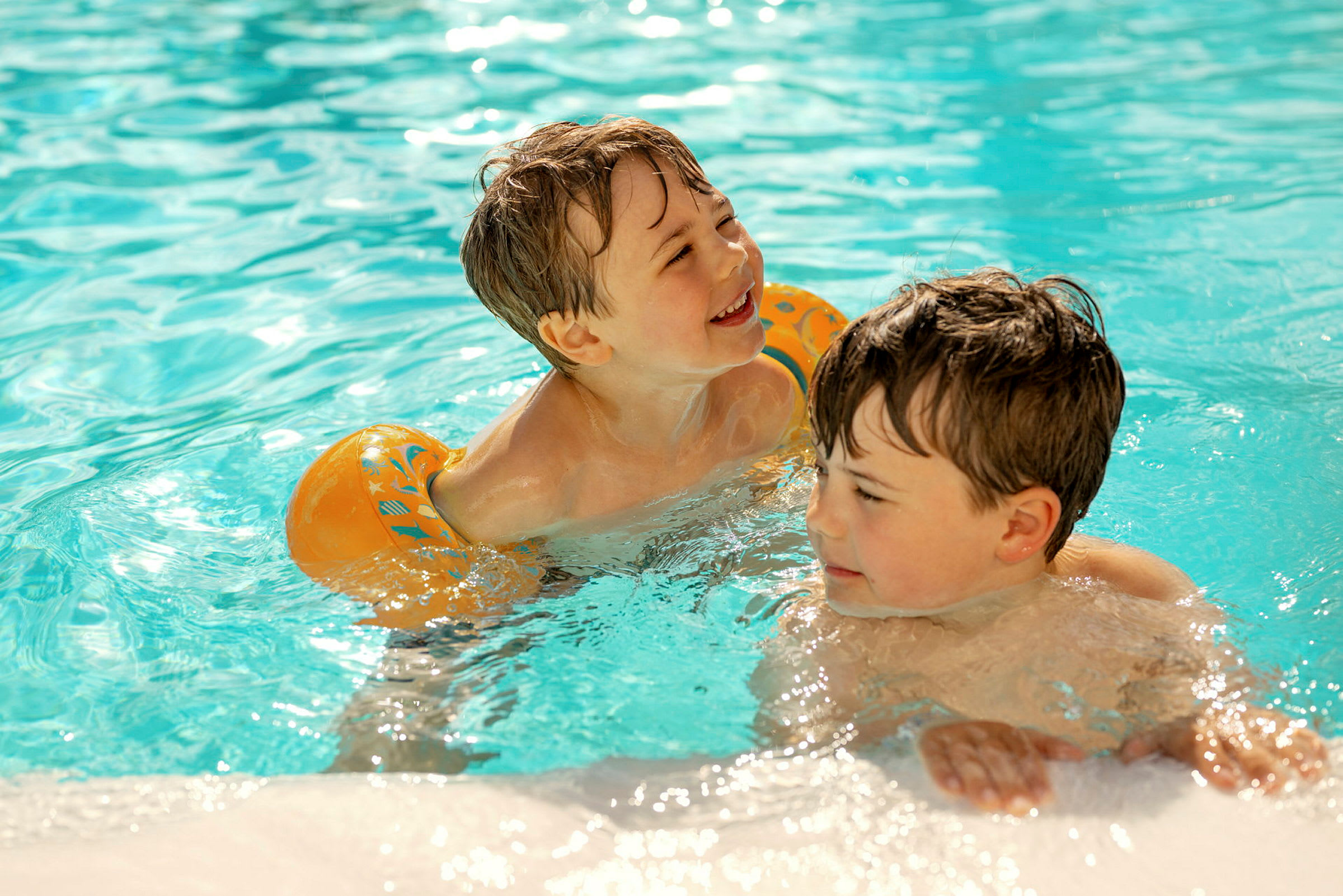 To børn leger i en swimmingpool fyldt med klart vand. (AI-genereret tekst)