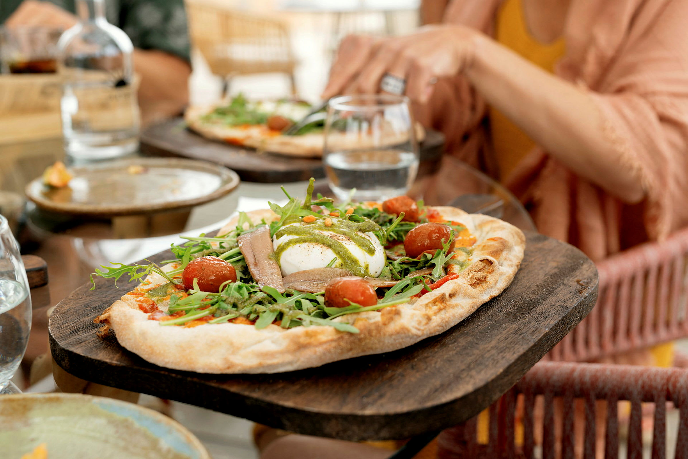 Et nærbillede af en pizza med rucola, cherrytomater og mozzarella. (AI-genereret tekst)