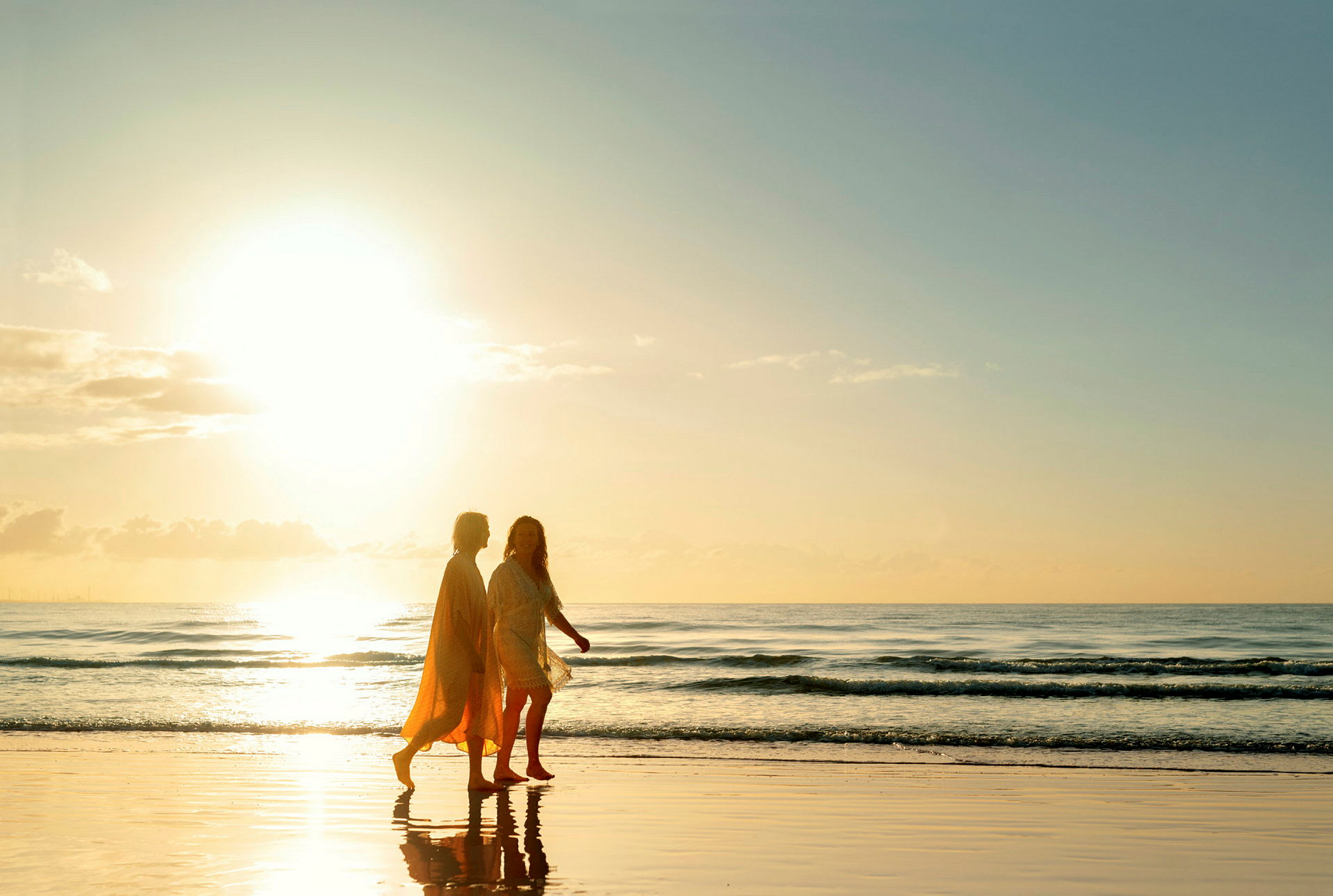 To personer går på en strand ved solnedgang. (AI-genereret tekst)