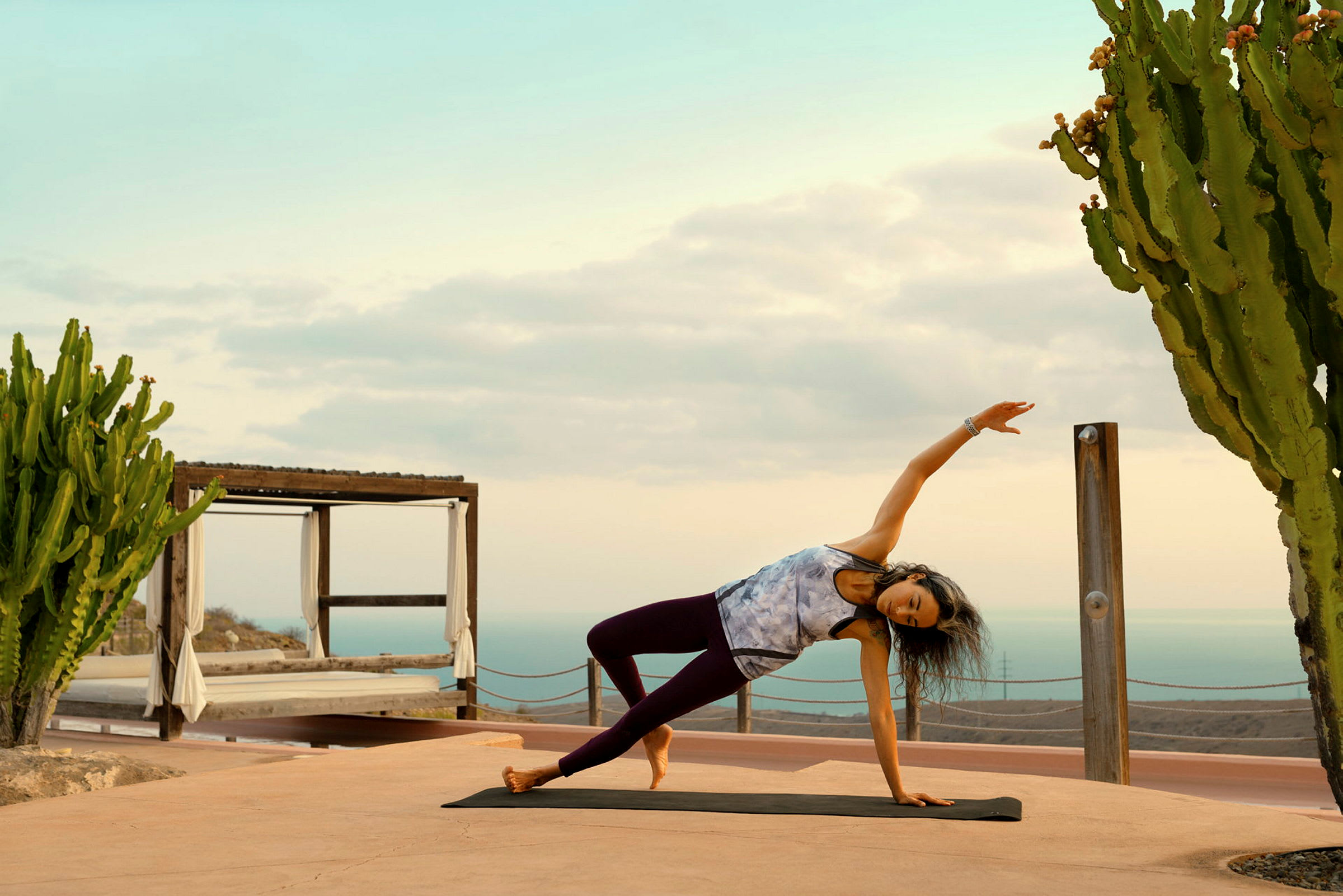 Person laver yoga på en måtte udendørs ved siden af en kaktus. (AI-genereret tekst)
