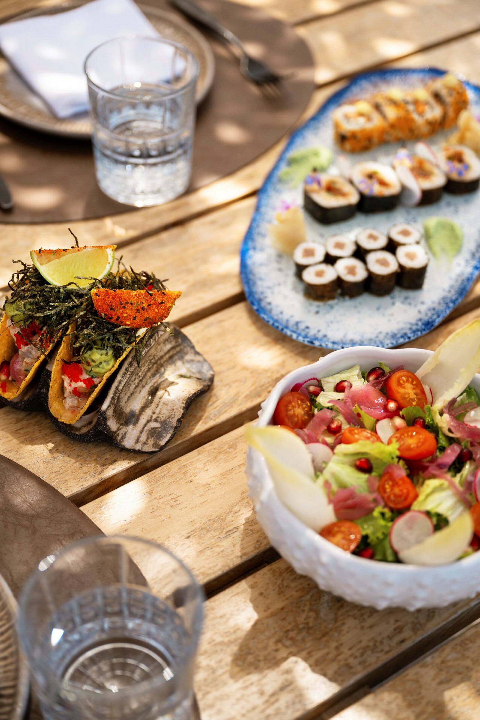 Bordopdækning med salat, sushi og små tacos. (AI-genereret tekst)