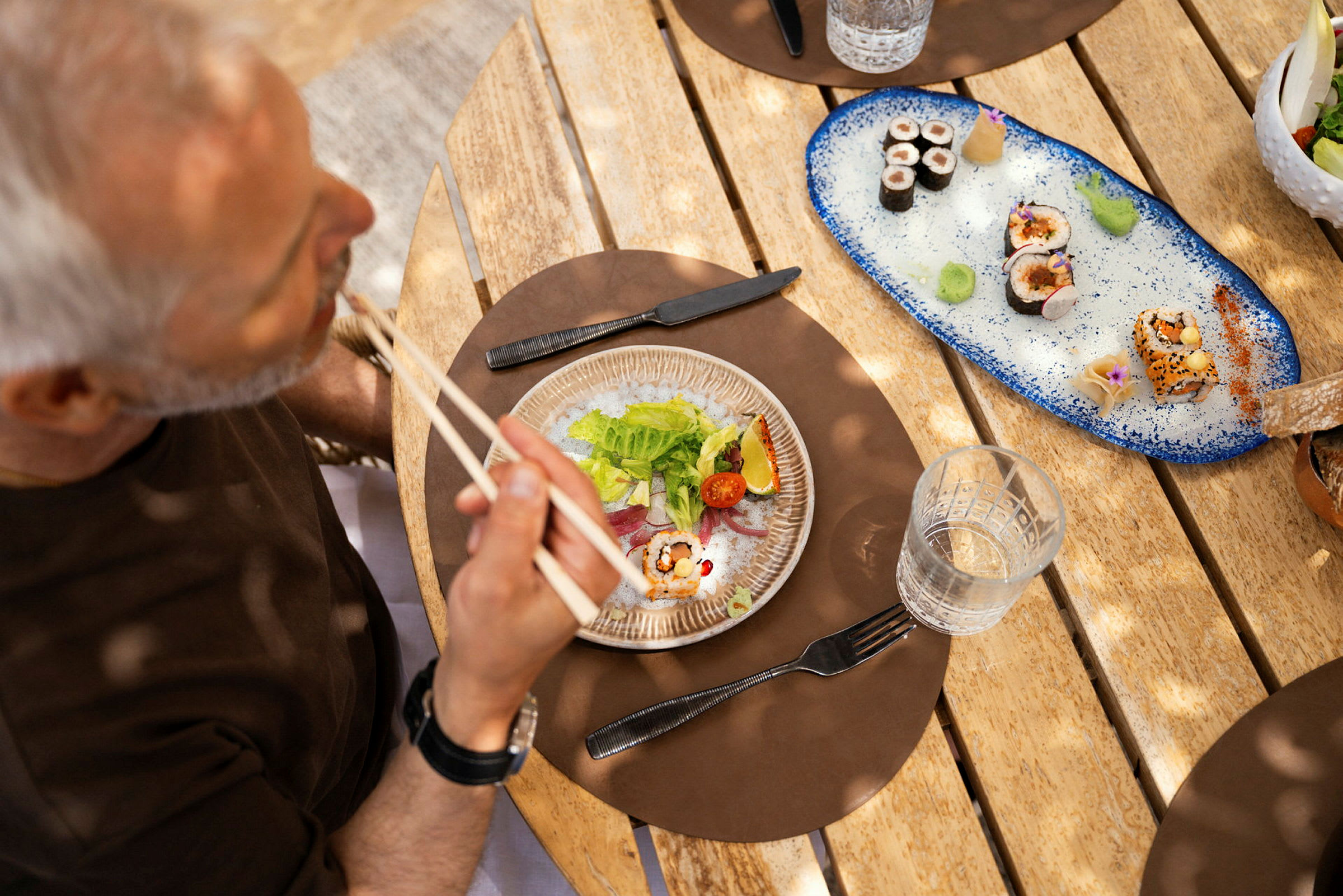 En person spiser sushi ved et træbord. (AI-genereret tekst)