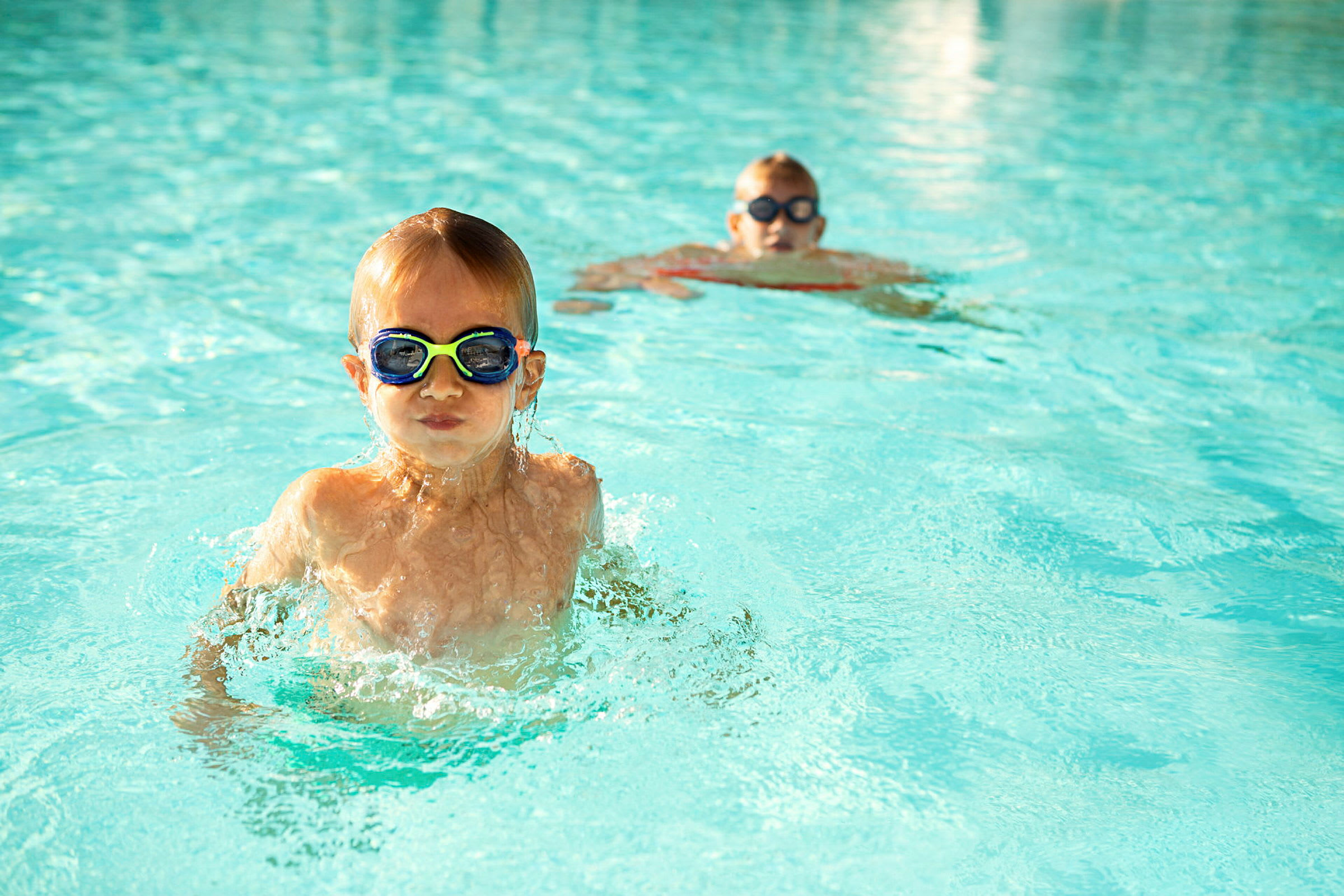 To personer svømmer i en pool med klart vand. (AI-genereret tekst)