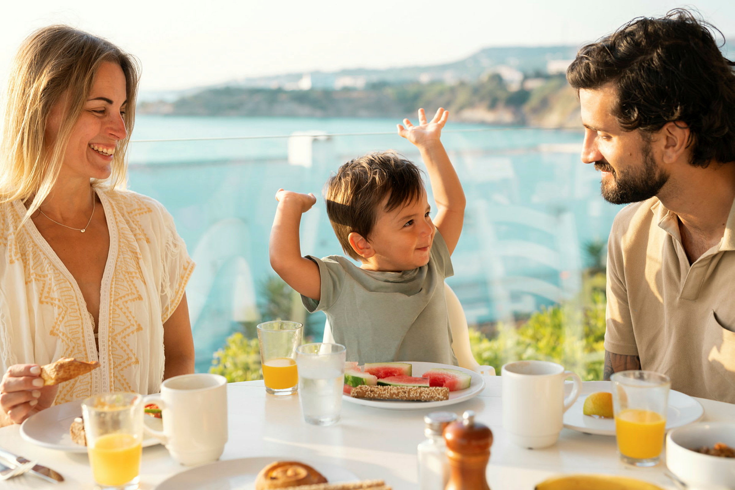En familie spiser morgenmad ved et bord med udsigt over havet. (AI-genereret tekst)