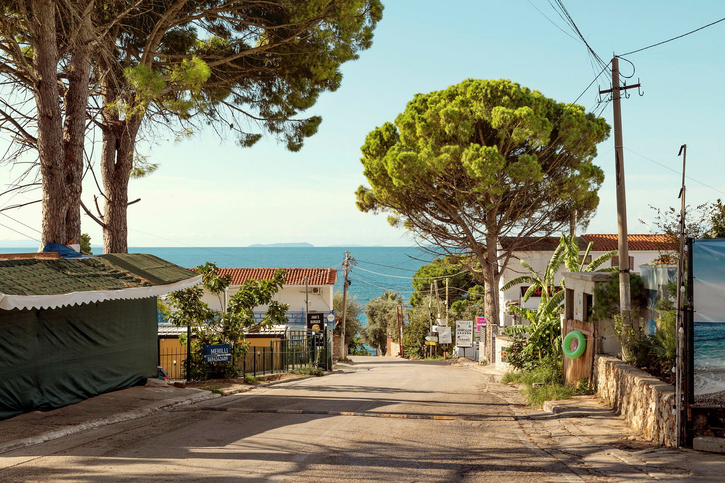 En rolig landevej med huse, træer og havet i baggrunden. (AI-genereret tekst)
