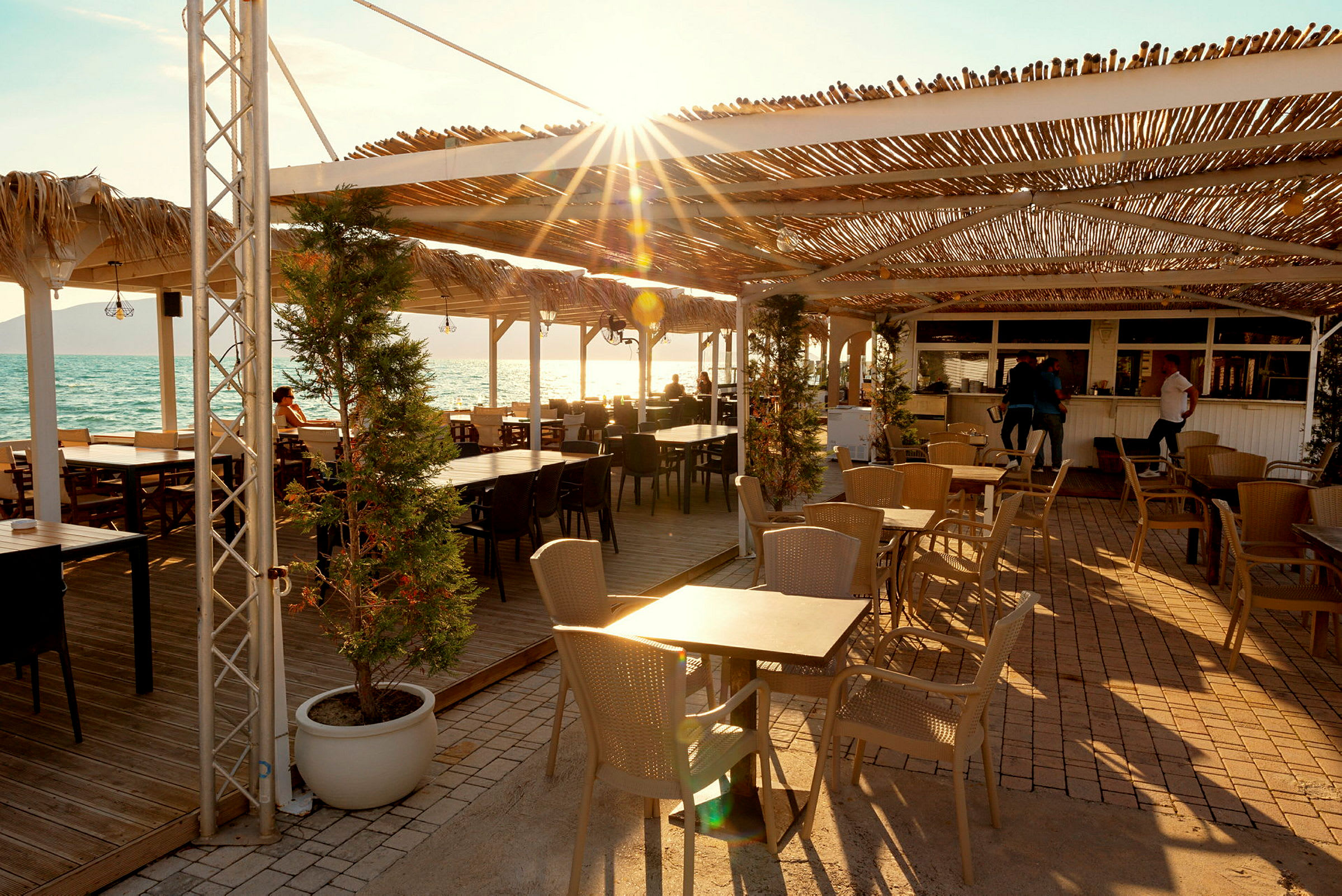 Strandnær restaurant med tag og udendørs servering. (AI-genereret tekst)