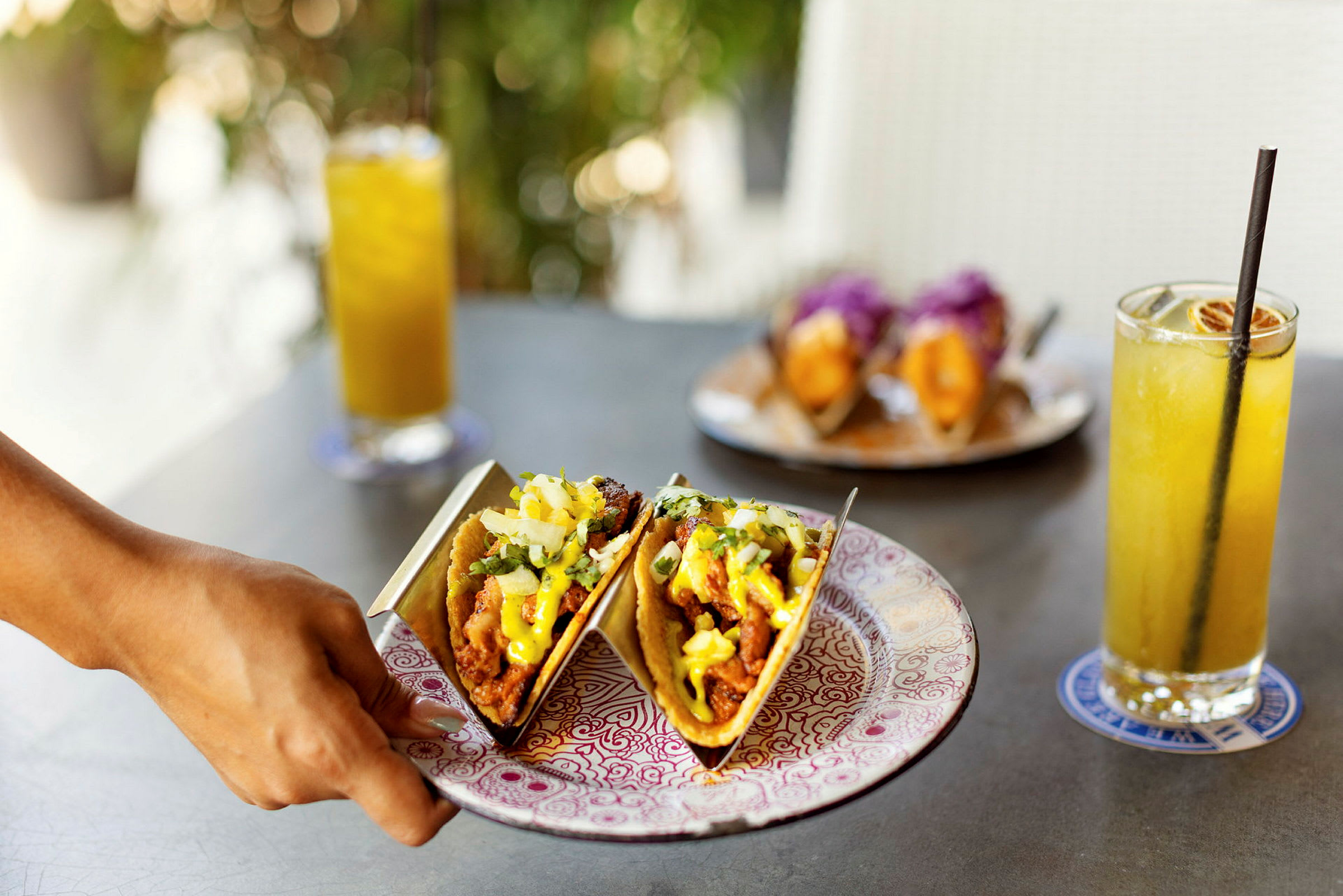 To tacos på en tallerken med drikkevarer i baggrunden. (AI-genereret tekst)