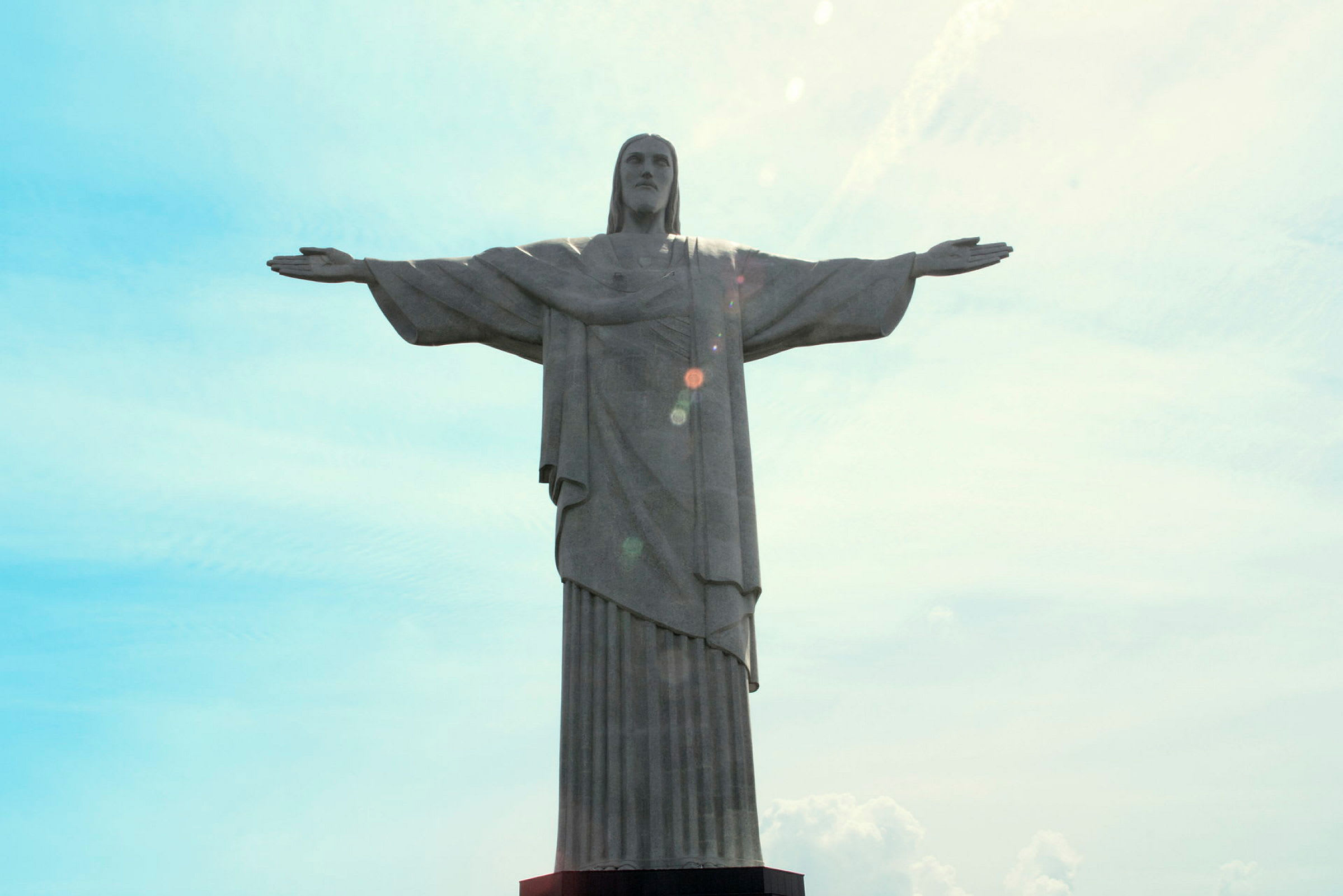 En statue af en person med udstrakte arme mod en himmel som baggrund. (AI-genereret tekst)