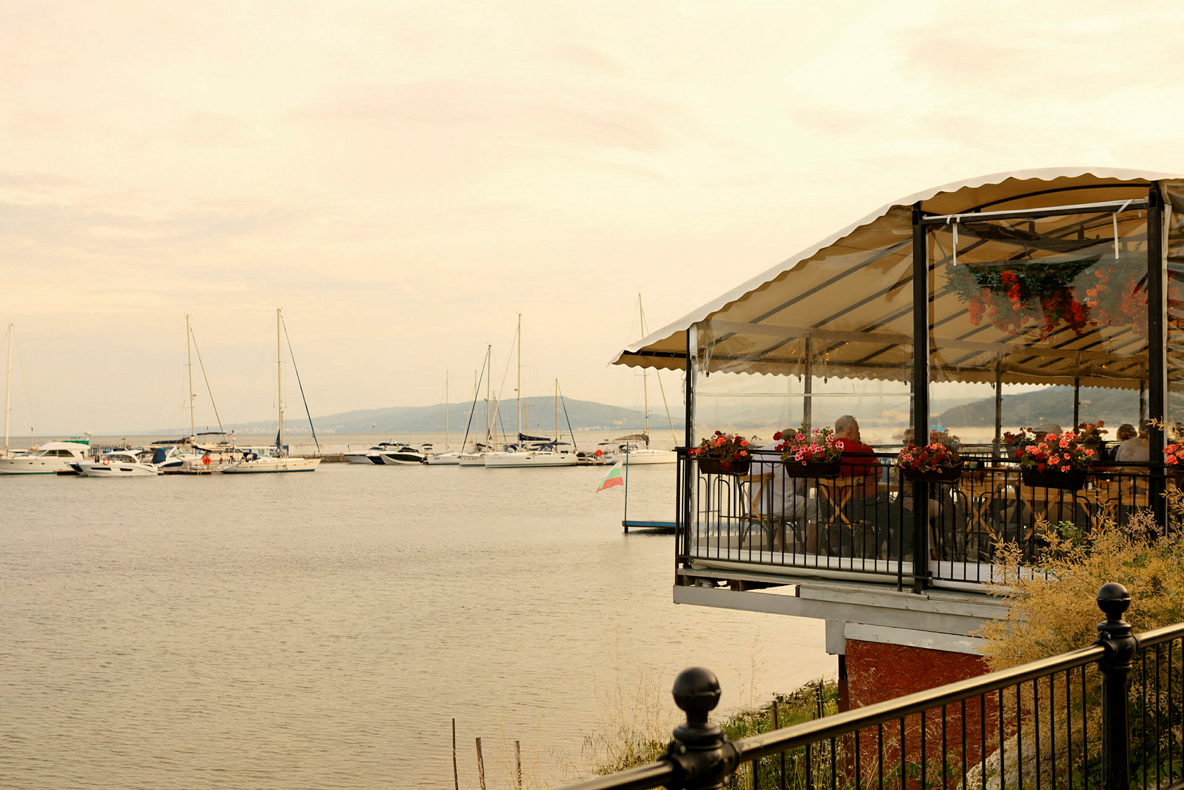 Restaurant med terrasse ved vandet og både i baggrunden. (AI-genereret tekst)