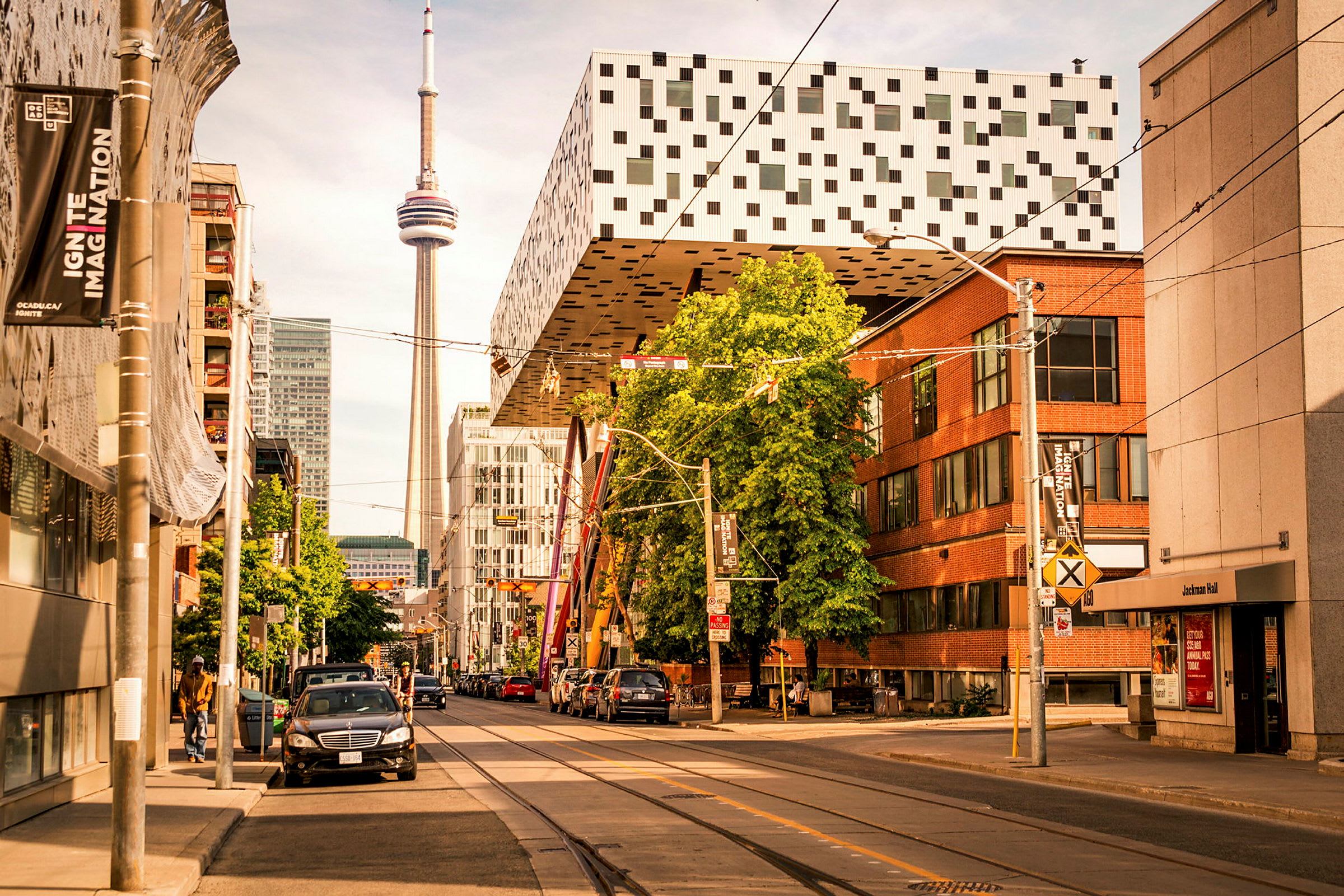 Gade med bygninger, parkering og CN Tower i baggrunden. (AI-genereret tekst)