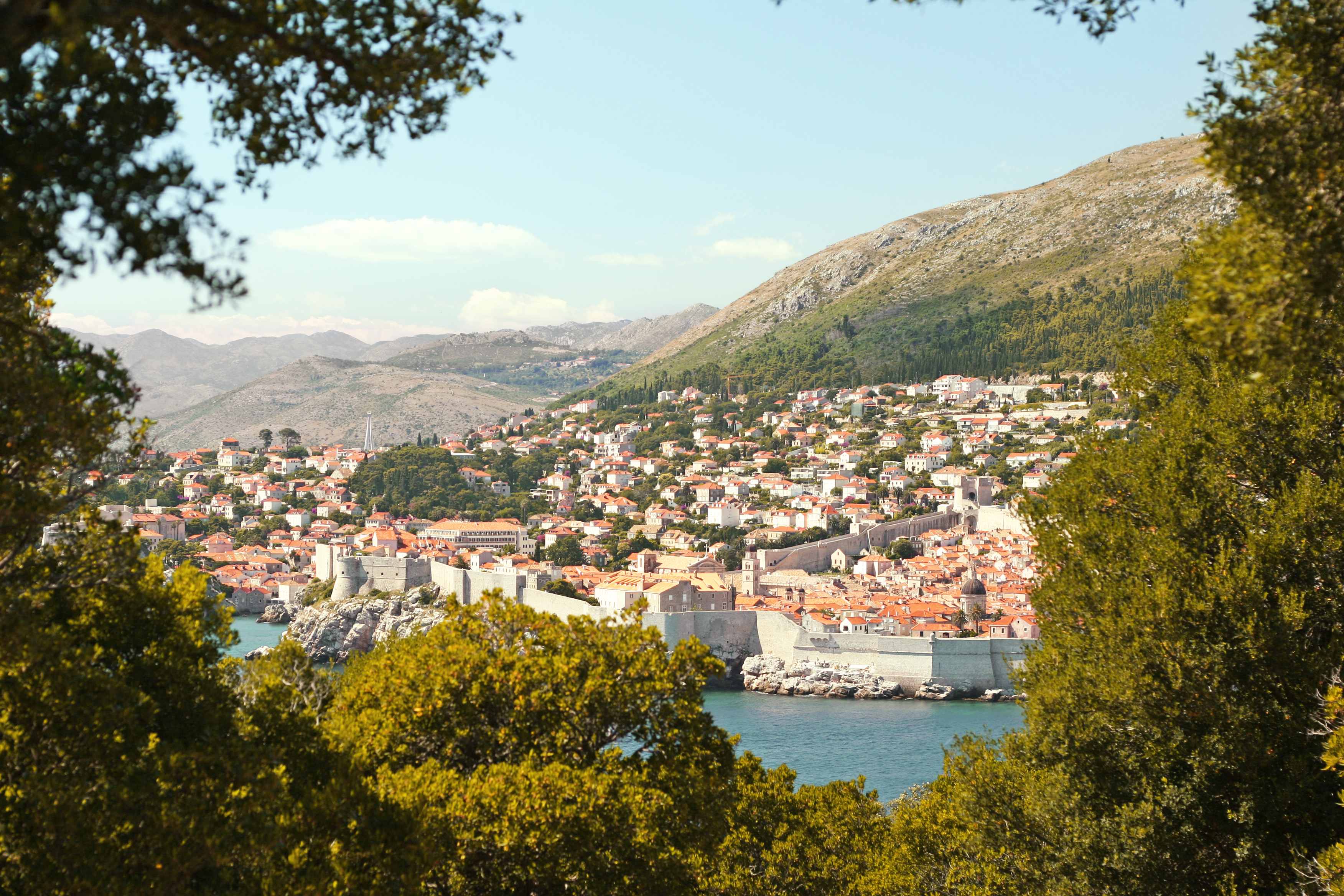 En udsigt over Dubrovnik med dens historiske bymur, omgivet af grønne områder. (AI-genereret tekst)
