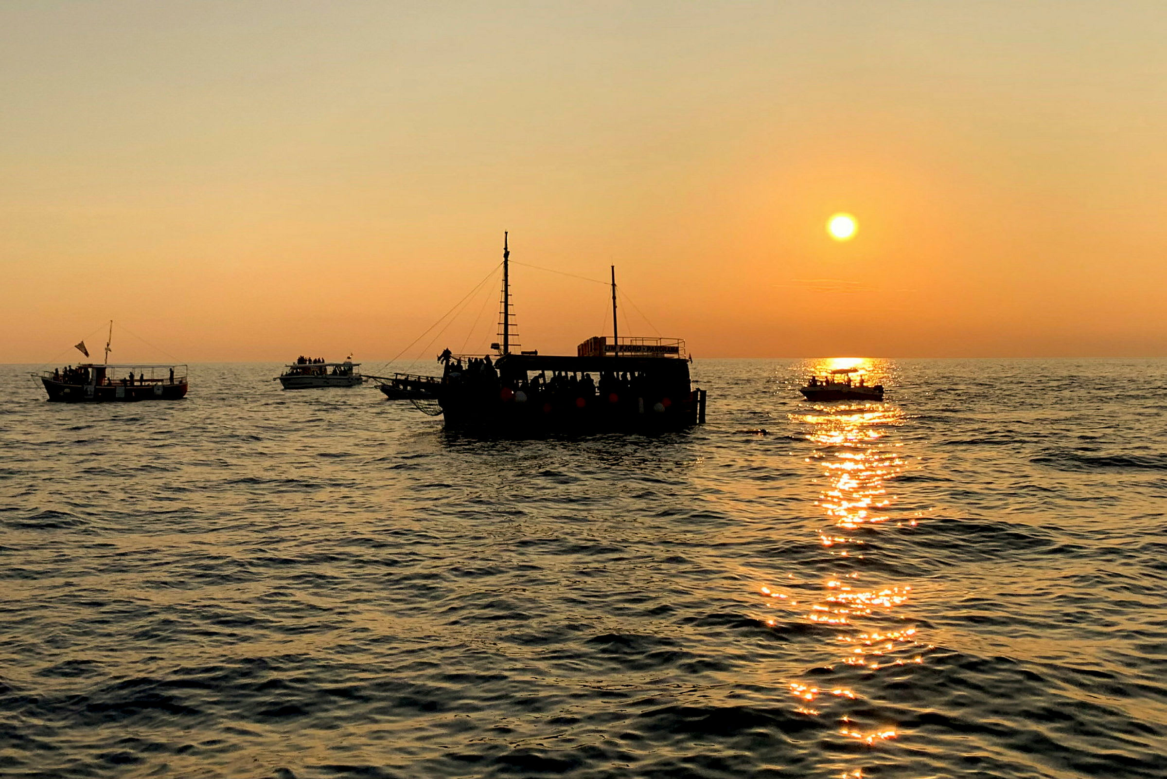 Flere både på havet ved solnedgang. (AI-genereret tekst)