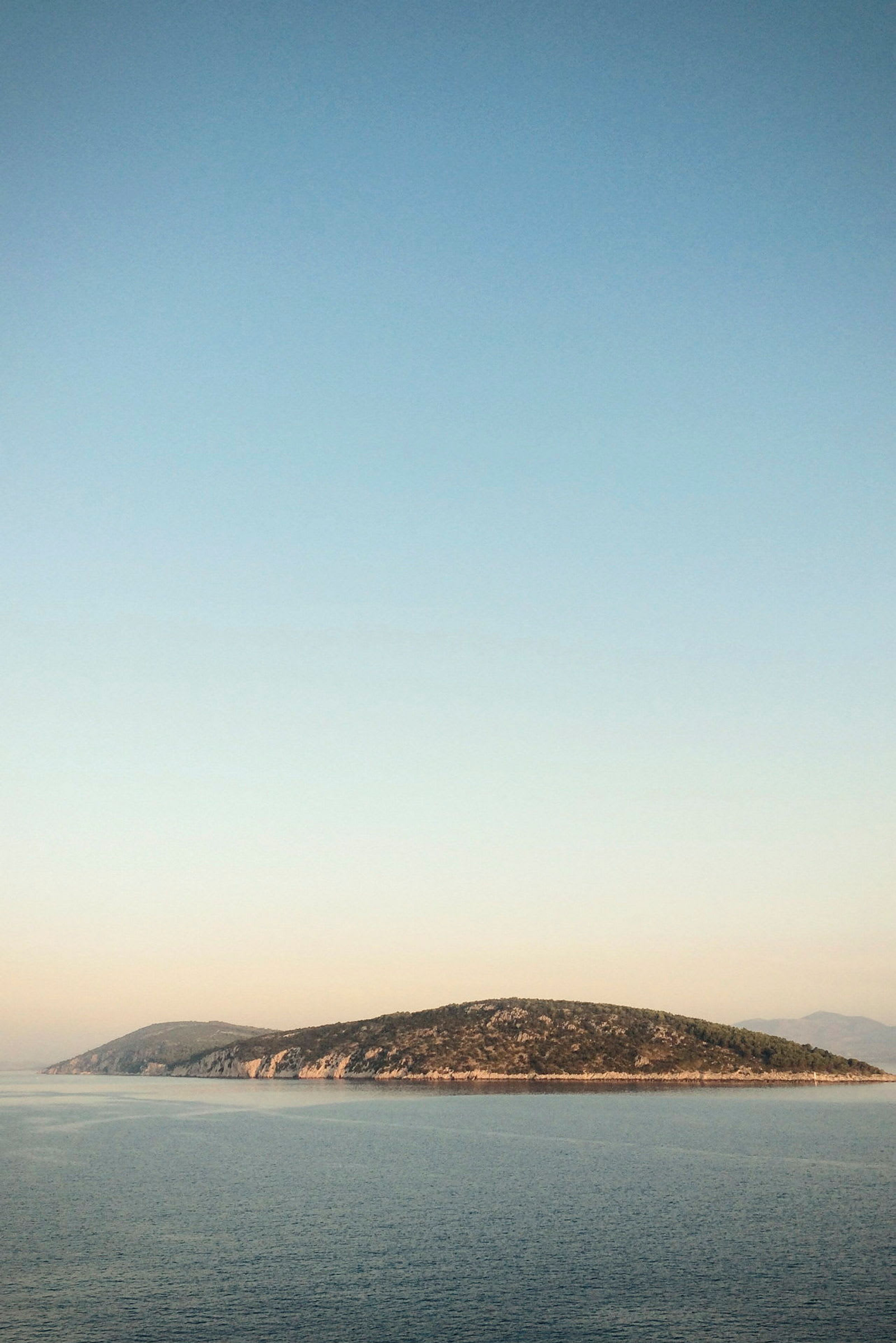 En lille ø i havet under en klar himmel. (AI-genereret tekst)