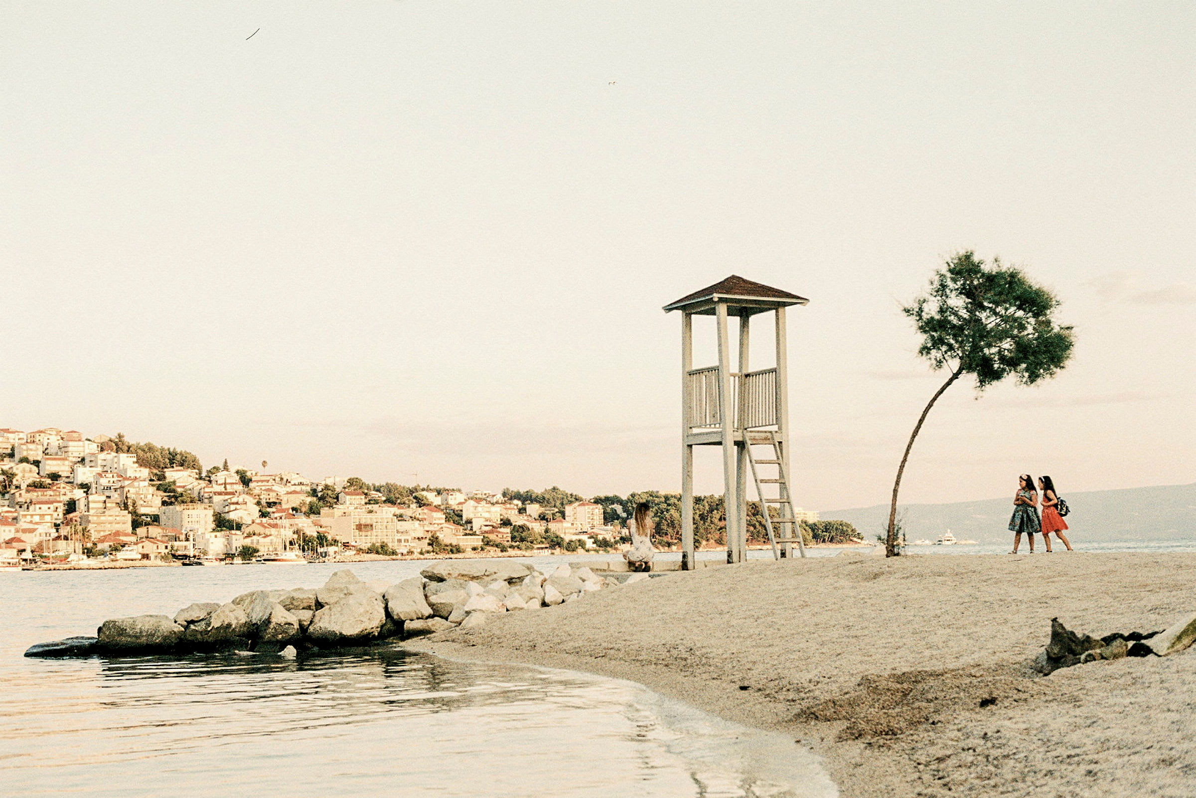 Vagtboks på en strand med to personer, der går tæt på et træ. (AI-genereret tekst)