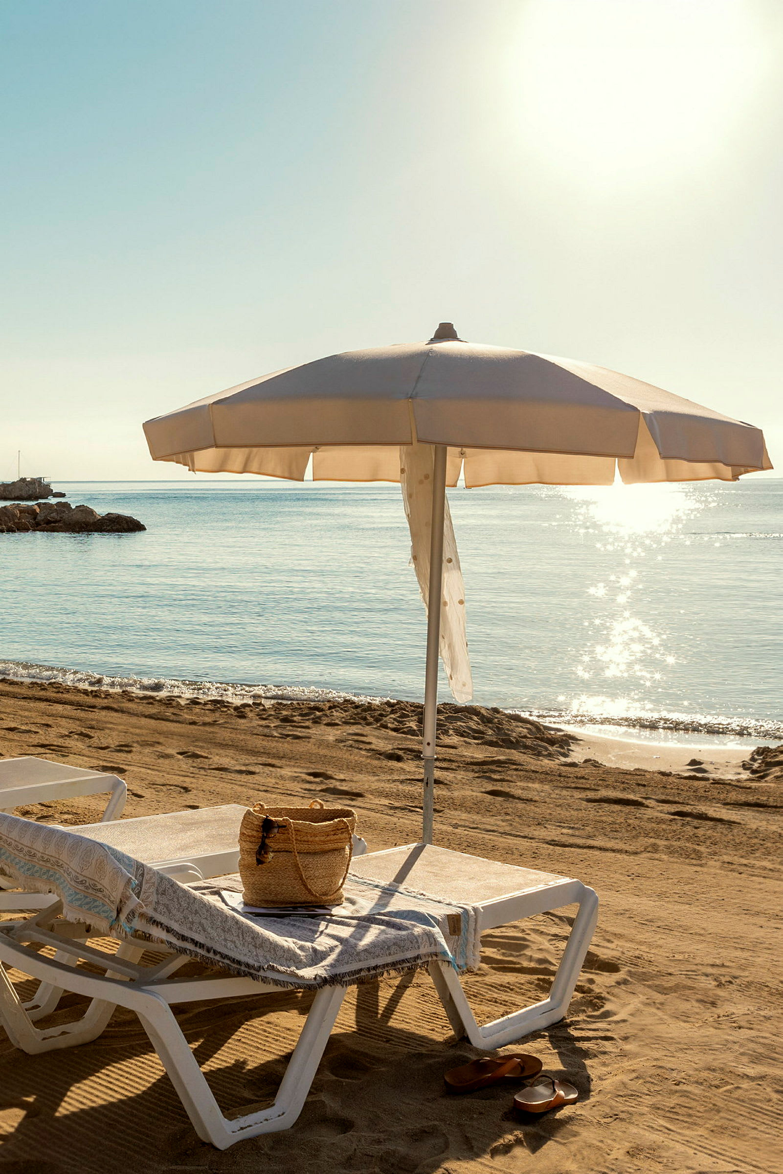 Strand med solseng og parasol tæt ved havet. (AI-genereret tekst)