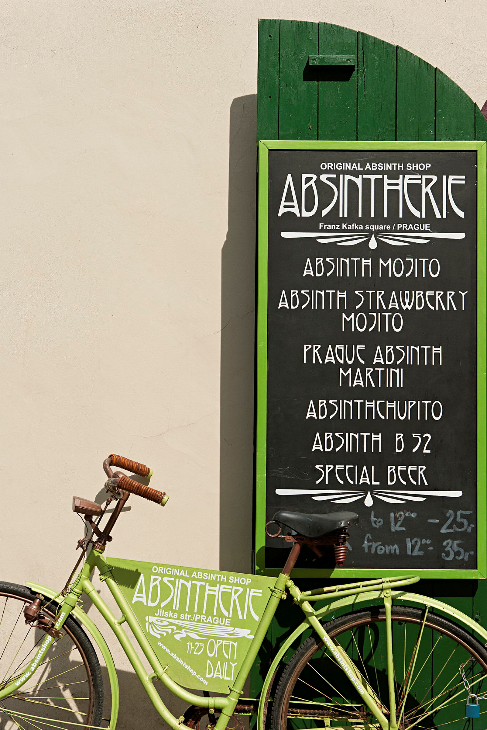 En grøn cykel foran et grønt skilt med menu fra en absintbutik. (AI-genereret tekst)