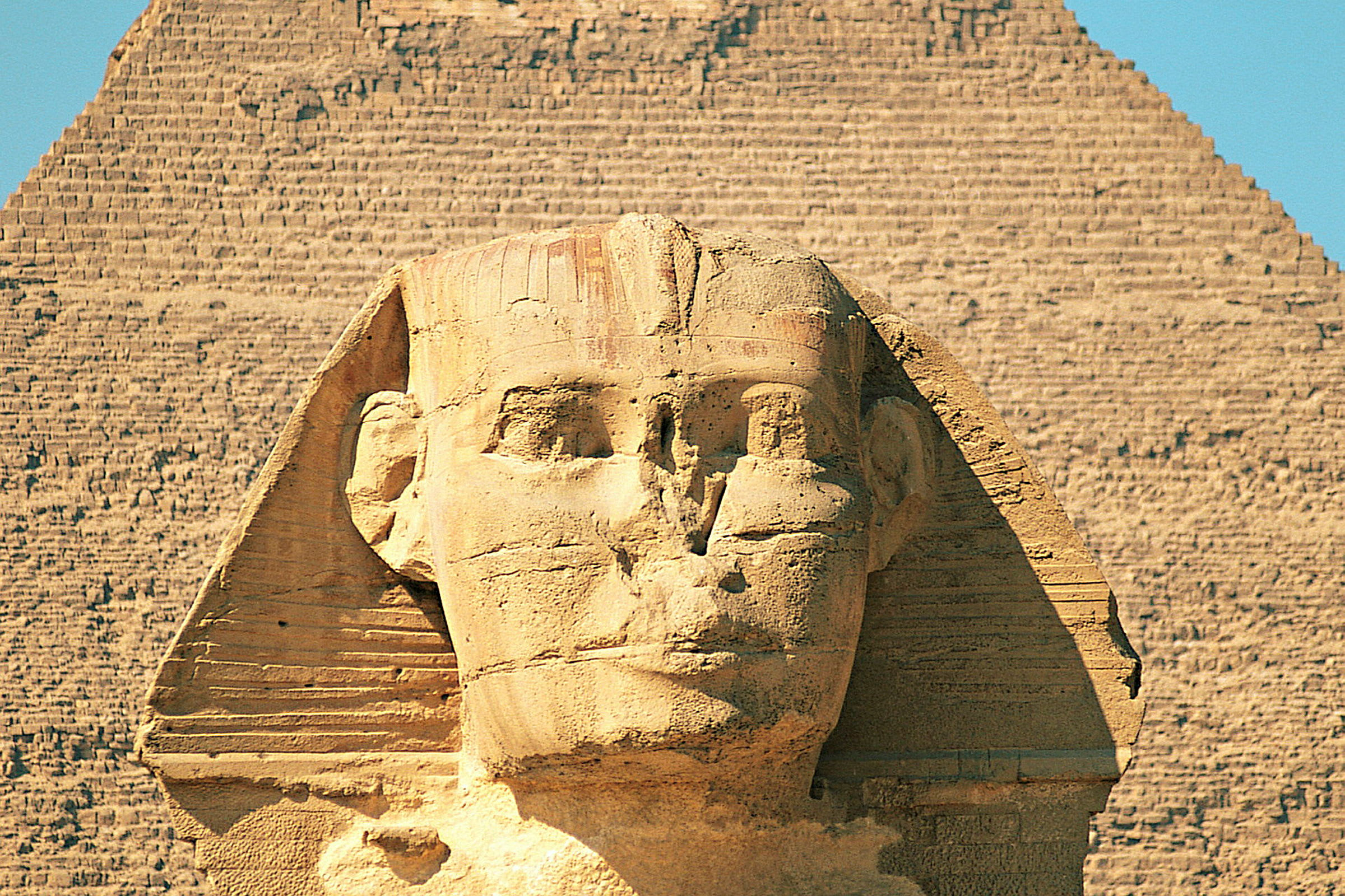 Billede af Sfinksen i Giza med en pyramide i baggrunden. (AI-genereret tekst)
