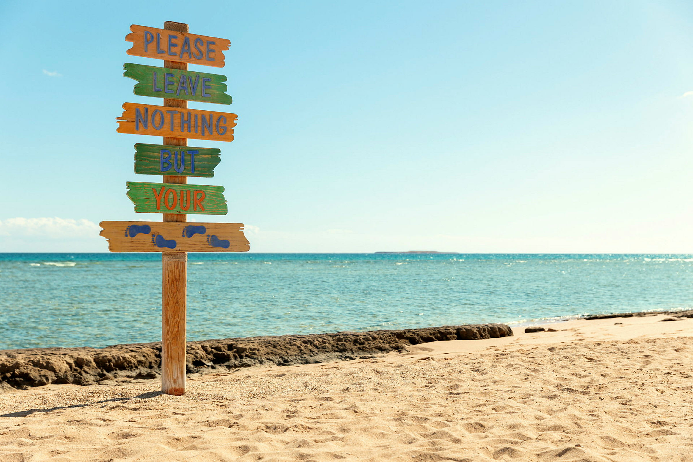 Skilt på strand med tekst, der opfordrer til ikke at efterlade affald. (AI-genereret tekst)
