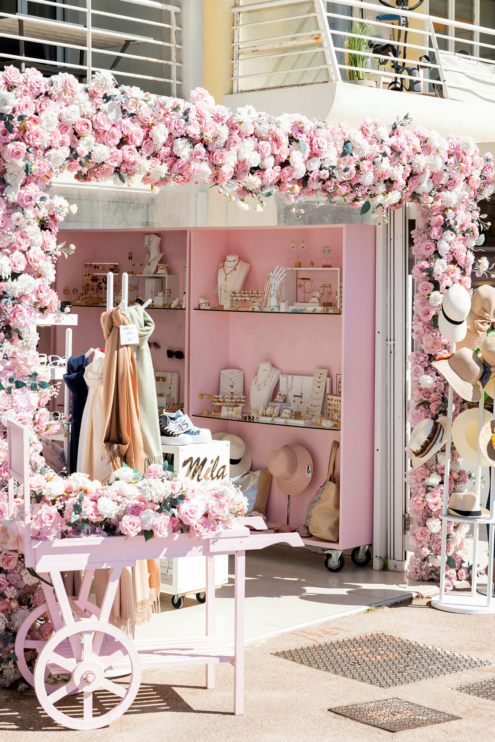 En butik med lyserøde dekorationer og blomster, smykker og tilbehør vises. (AI-genereret tekst)