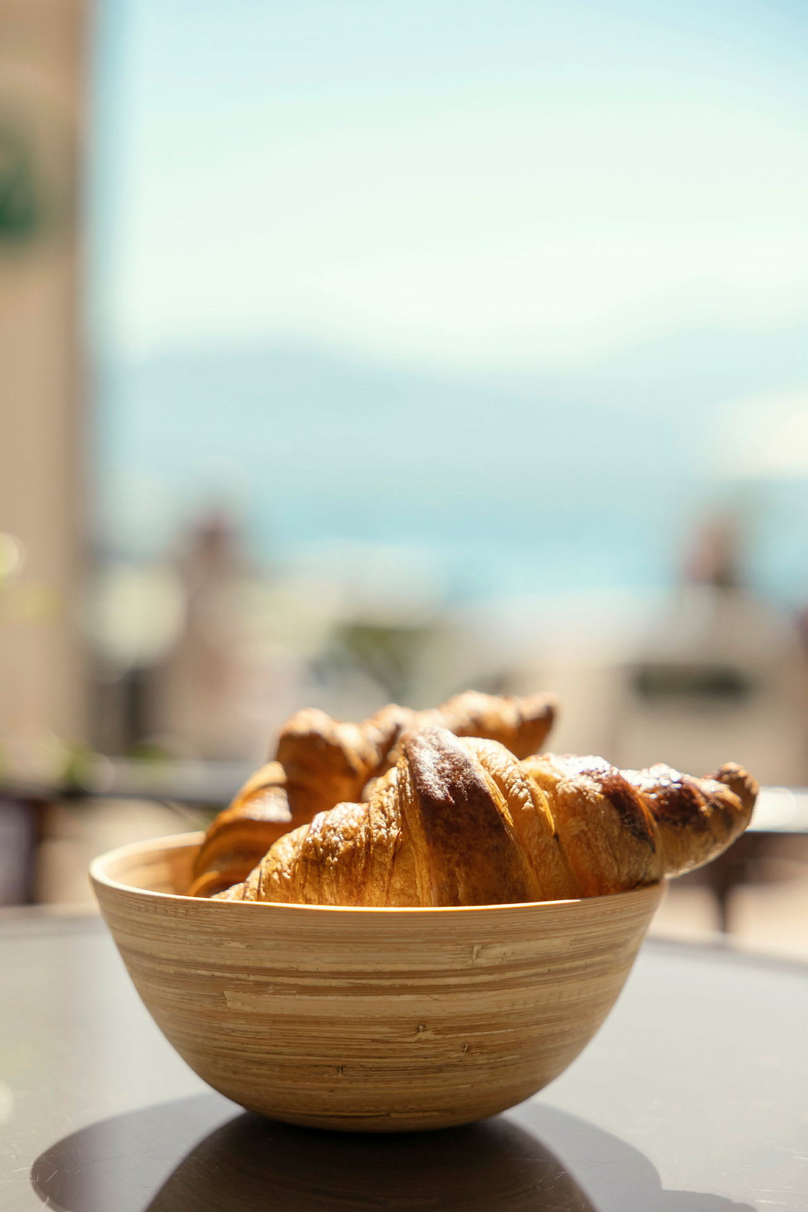En skål med croissanter står på et bord med sløret baggrund. (AI-genereret tekst)