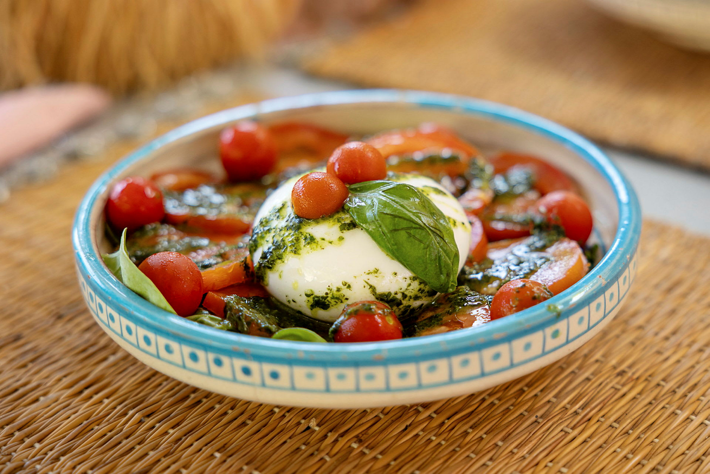 En tallerken med burrata, cherrytomater, frisk basilikum og pesto. (AI-genereret tekst)