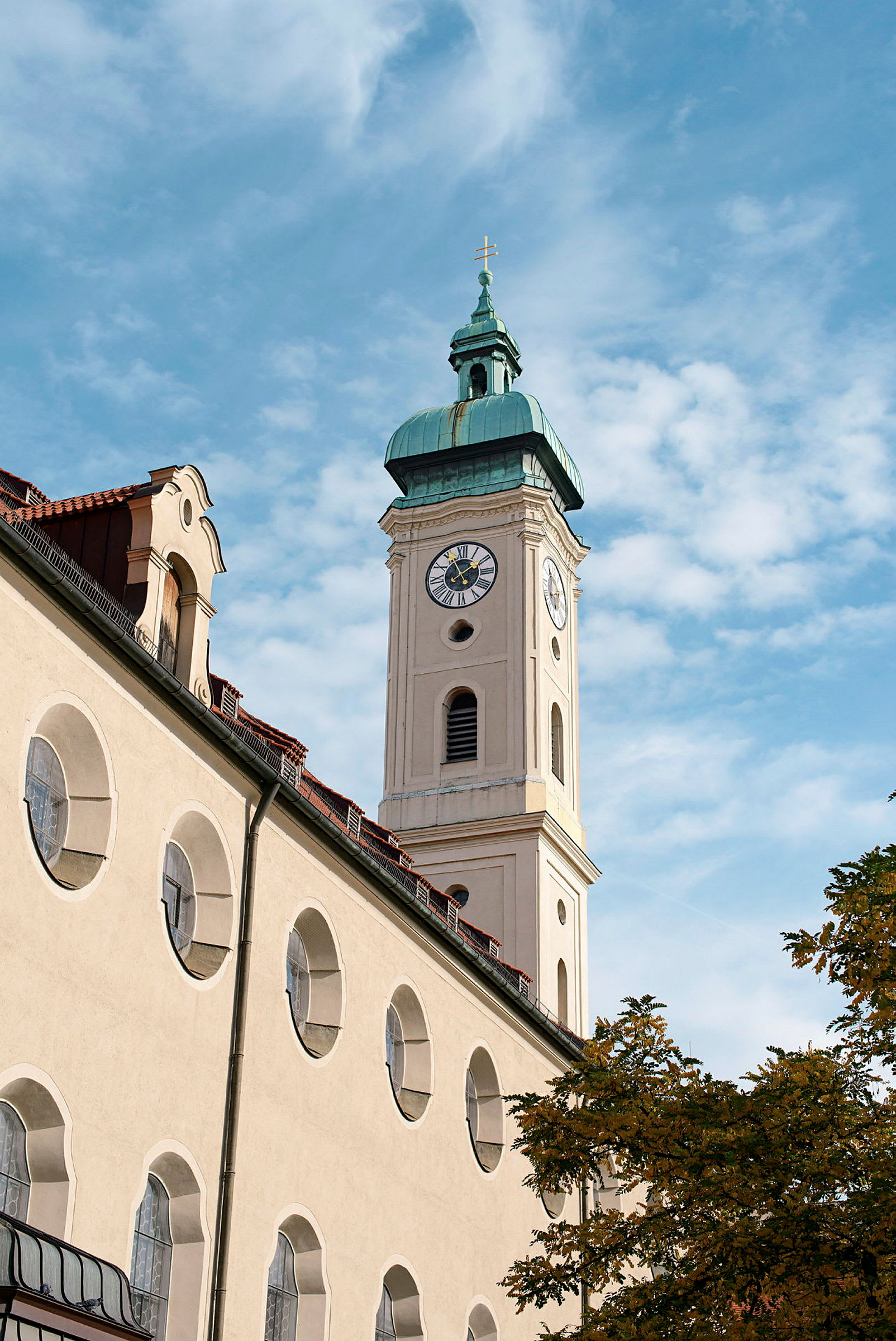 En kirke med et klokketårn og en spir med et kors på toppen, mod en blå himmel. (AI-genereret tekst)