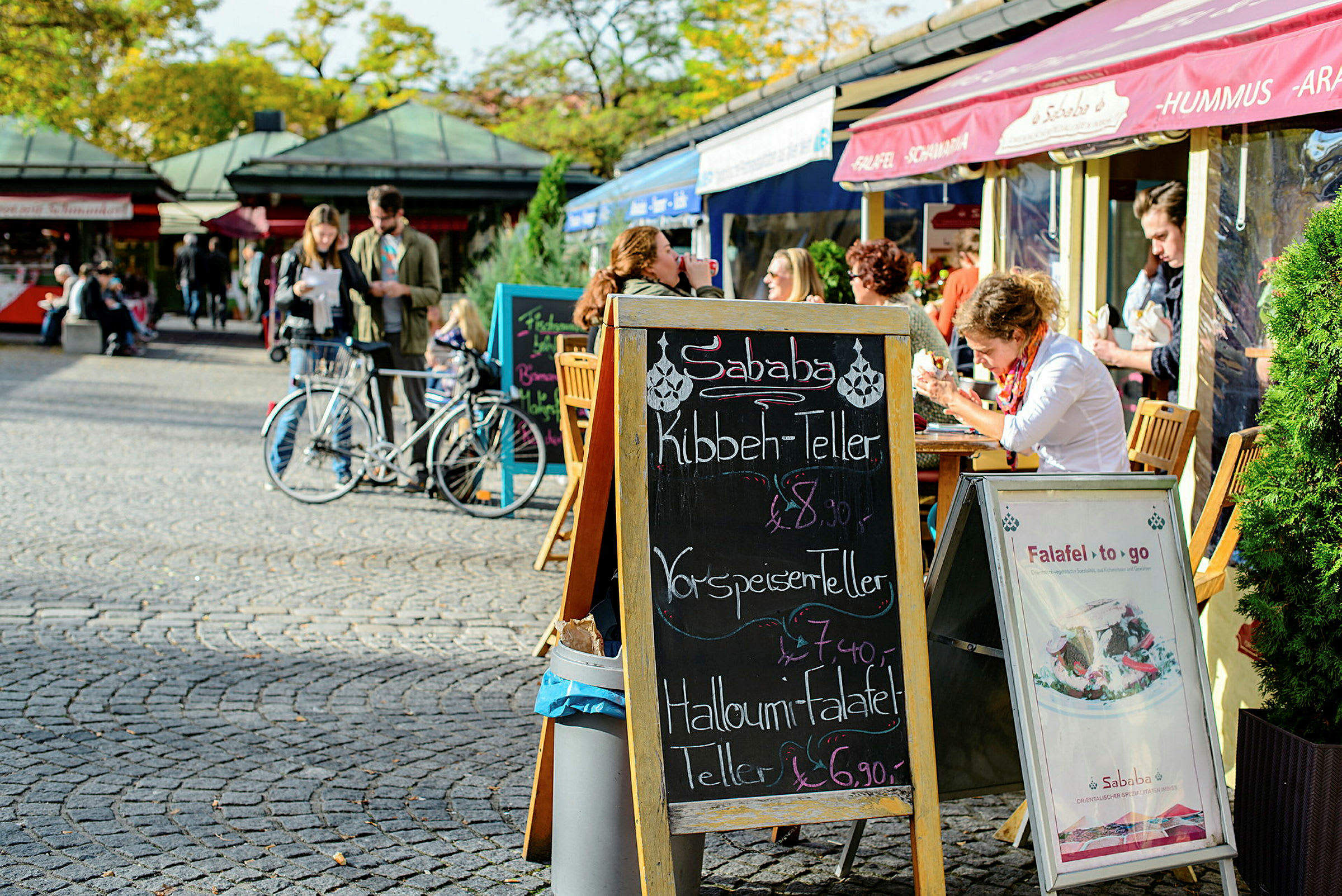 En gadecafé med udendørs servering og en menu på en sort tavle. (AI-genereret tekst)