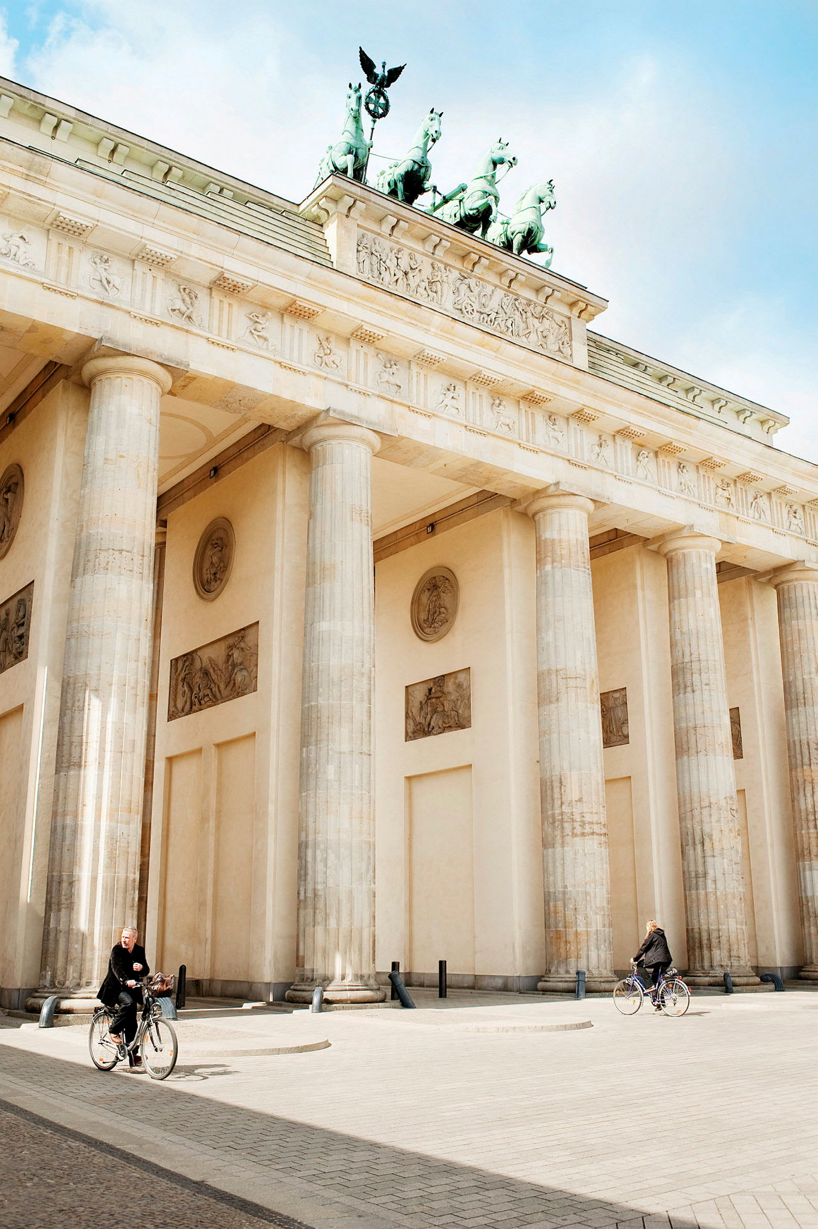 Brandenburger Tor med to cyklister foran. (AI-genereret tekst)