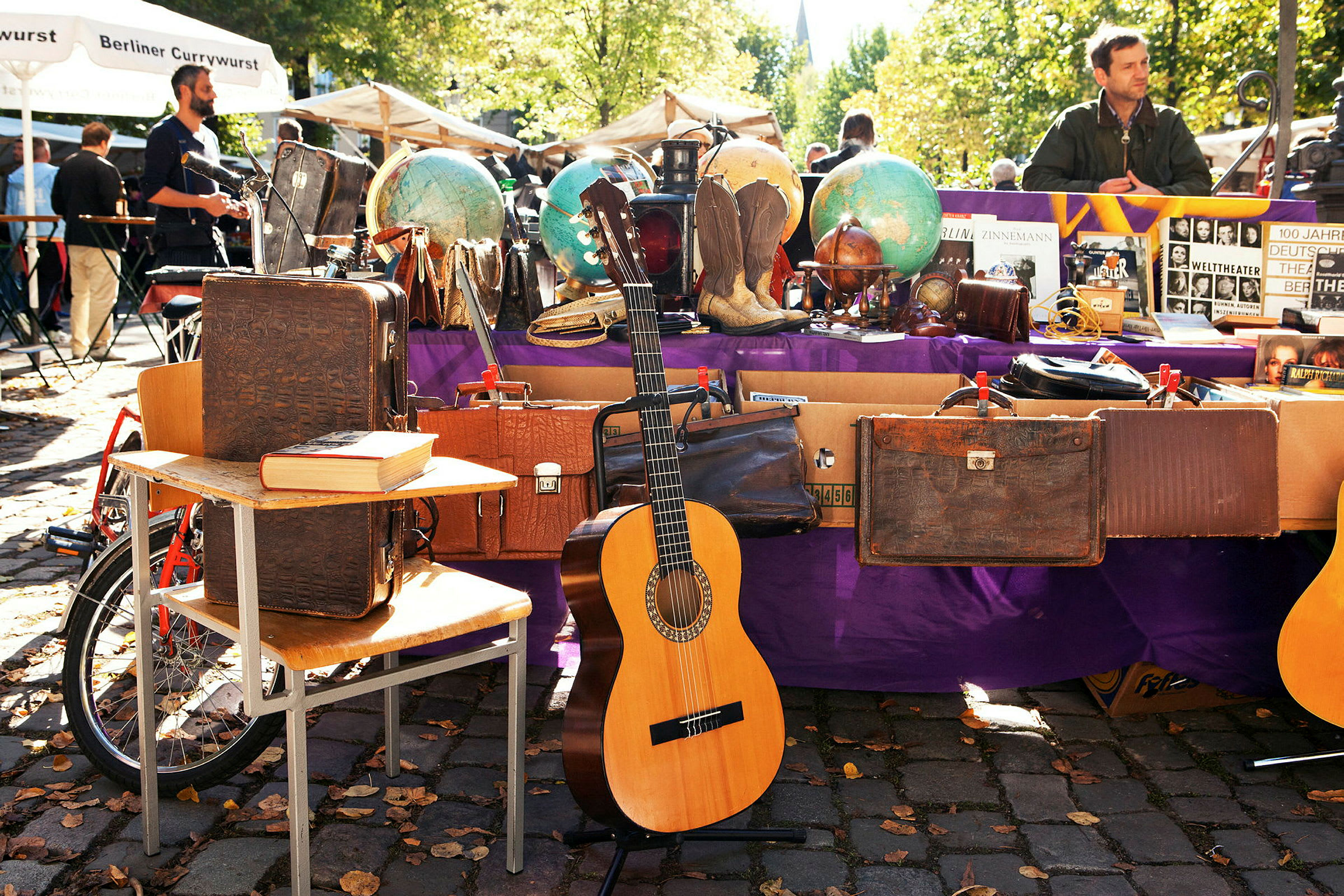 En markedsbod med vintageobjekter, herunder kufferter, globusser og en guitar. (AI-genereret tekst)
