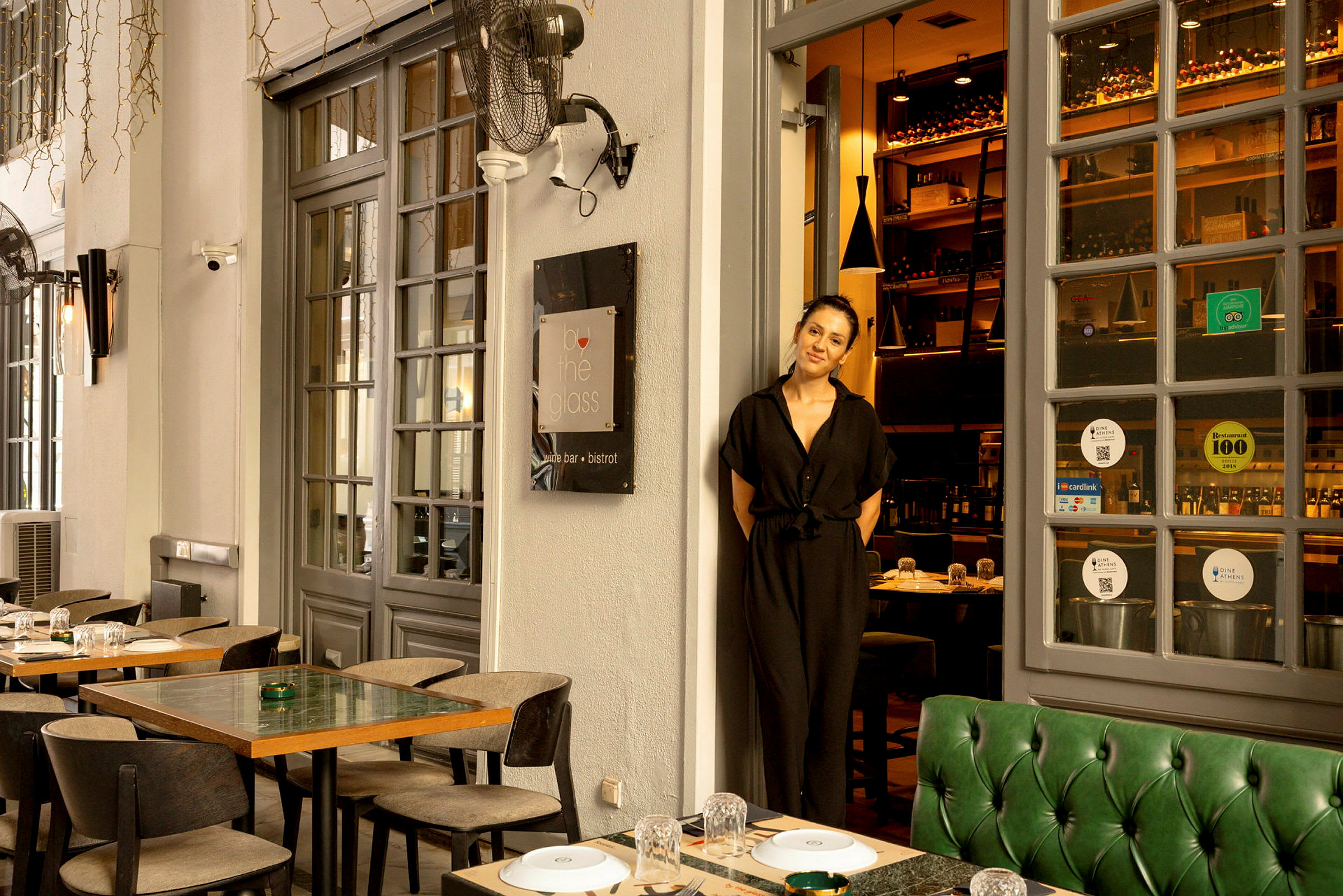 En restaurant med udendørsborde og glasdøre, der fører ind til en vinbar. (AI-genereret tekst)