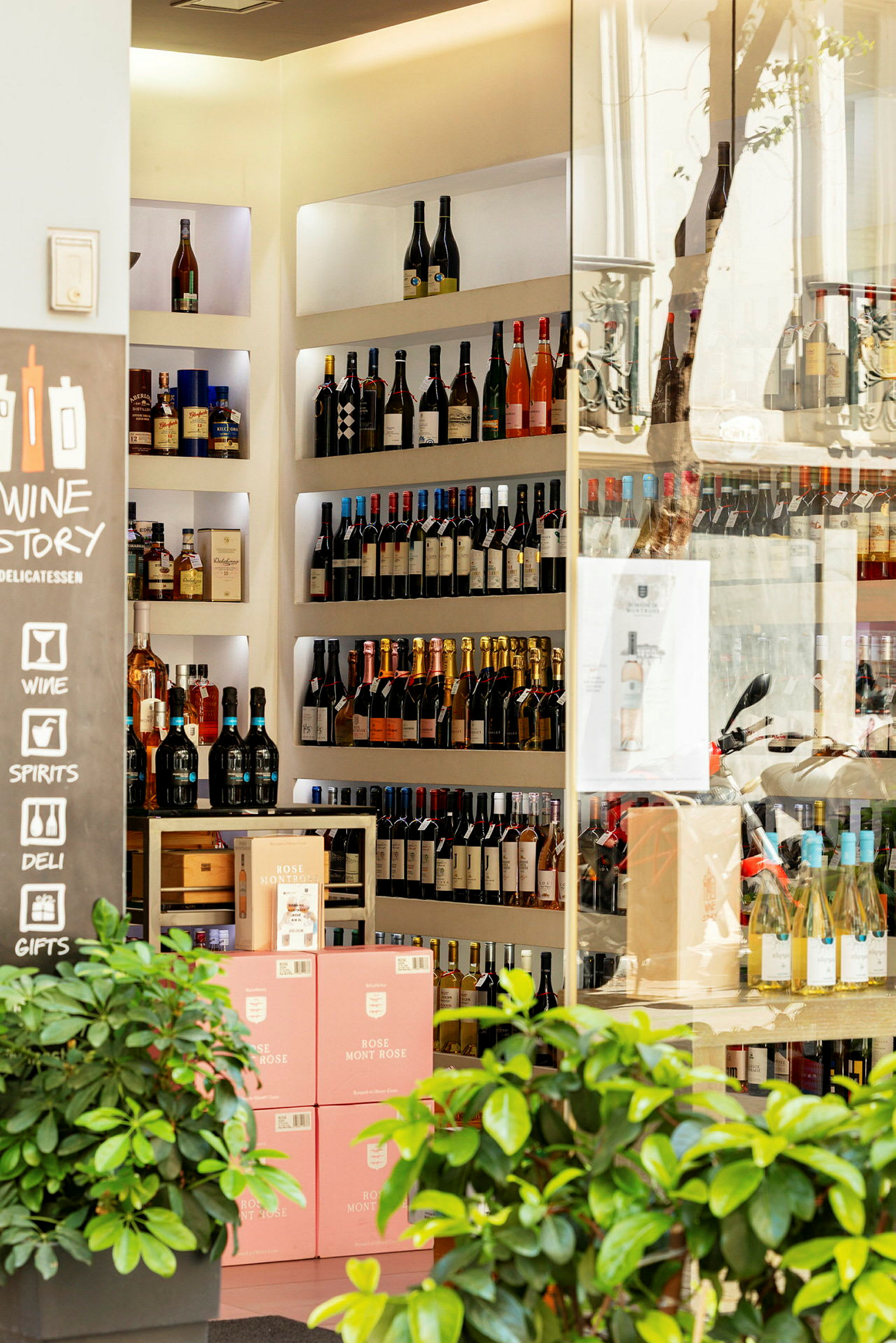 En vin- og spiritusbutik med hylder fyldt med flasker og kasser med lyserøde etiketter. (AI-genereret tekst)