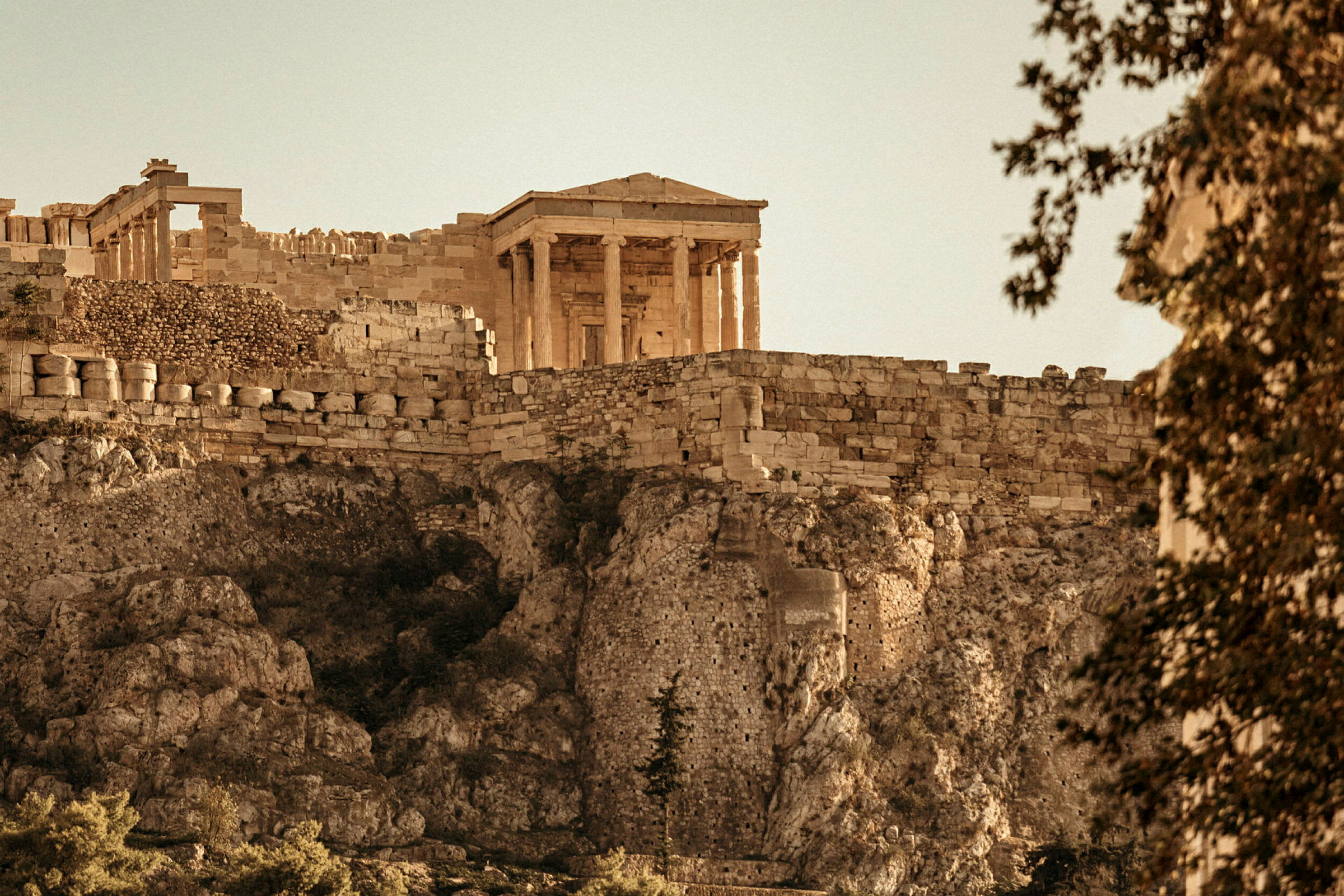 Et antikt tempel på Akropolis med stenmur og klipper. (AI-genereret tekst)