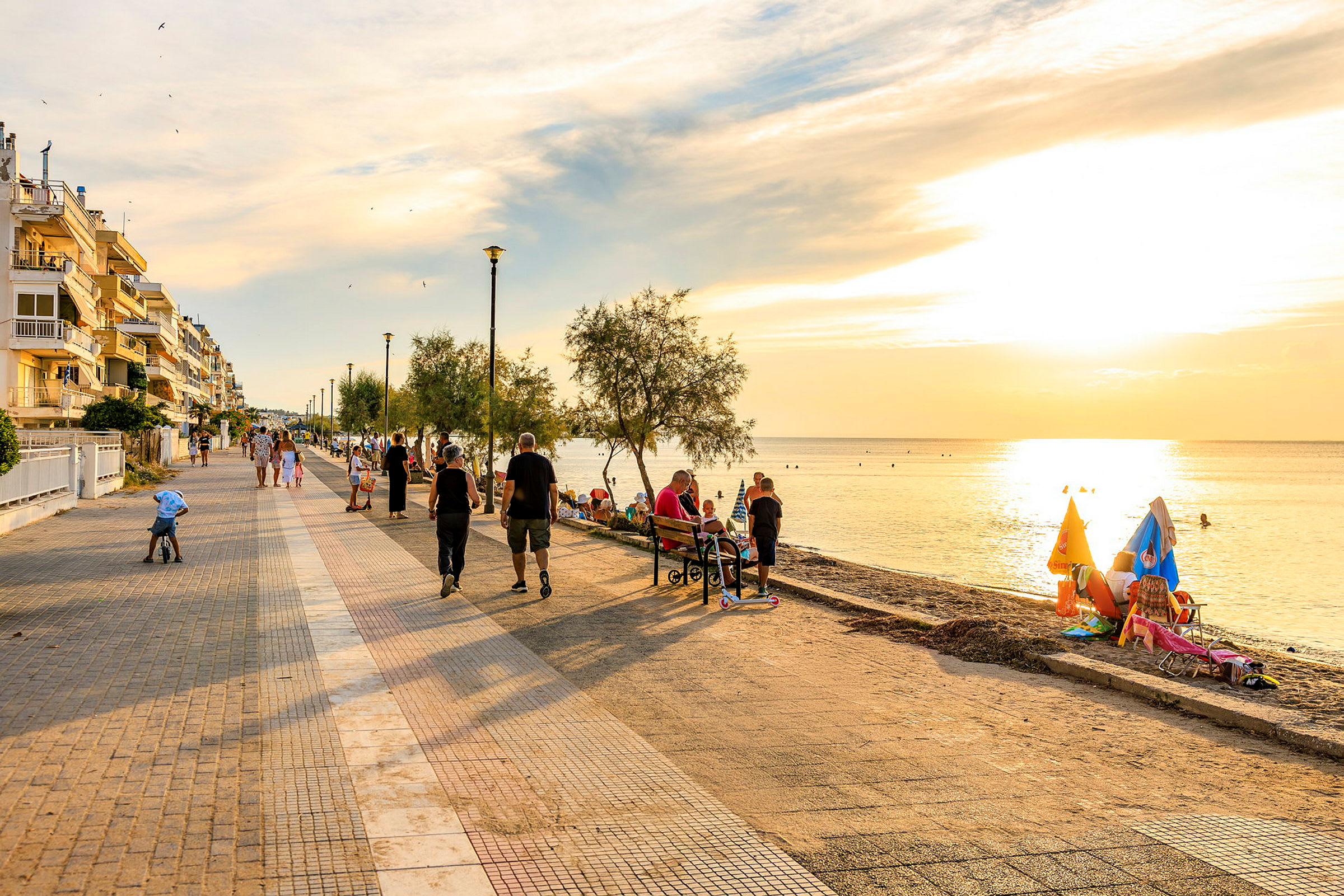 Promenade langs havet med mennesker, der går og sidder på bænke. (AI-genereret tekst)