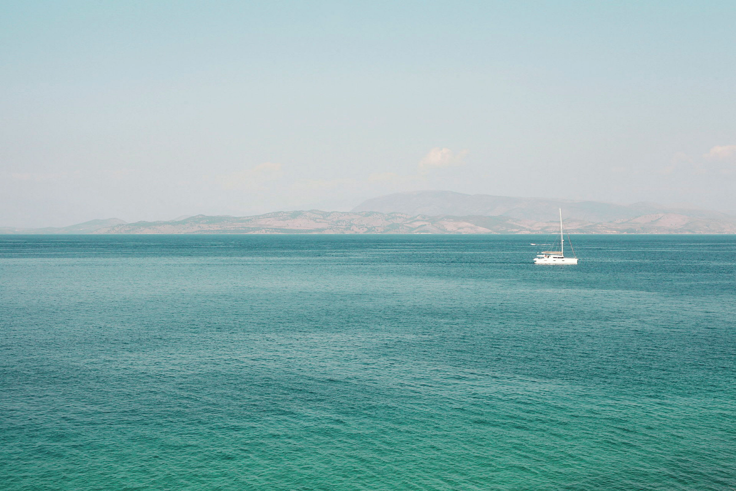 En sejlbåd på havet med bjerge i baggrunden. (AI-genereret tekst)
