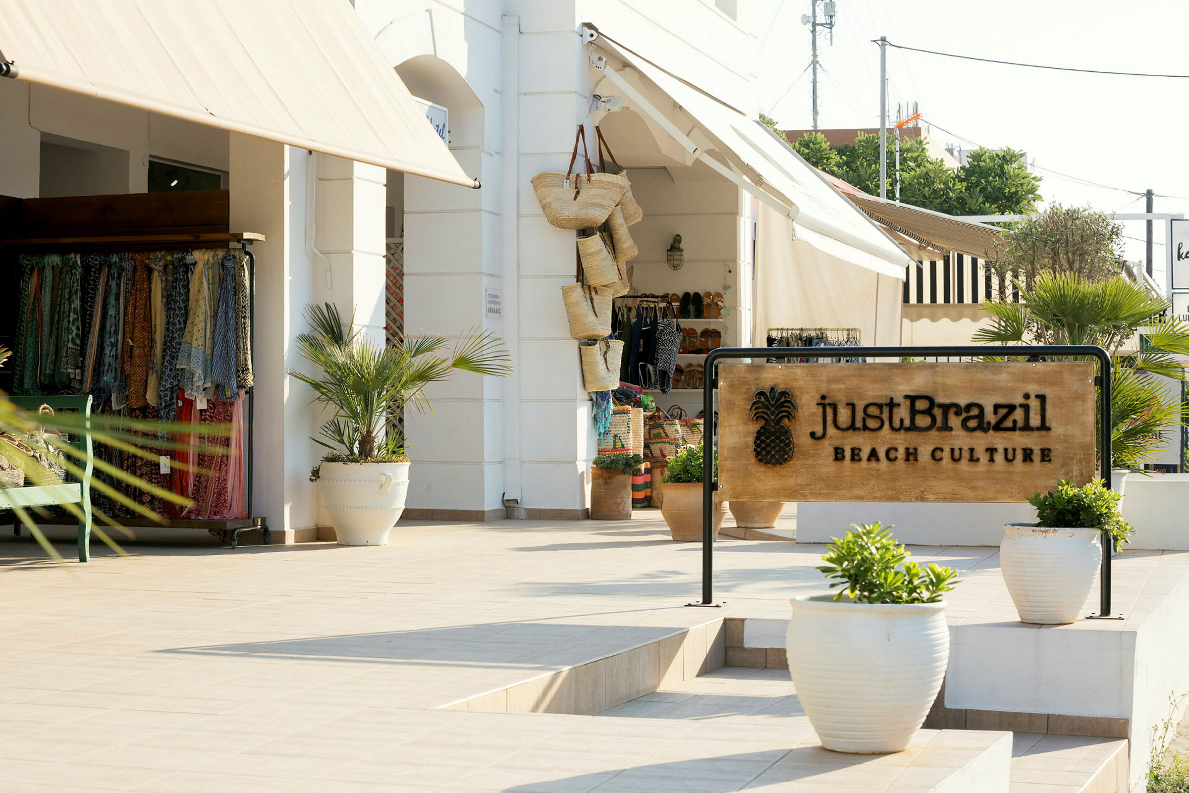 Skilt med teksten 'Just Brazil Beach Culture' foran en butik med bomuldstøj og kurve. (AI-genereret tekst)