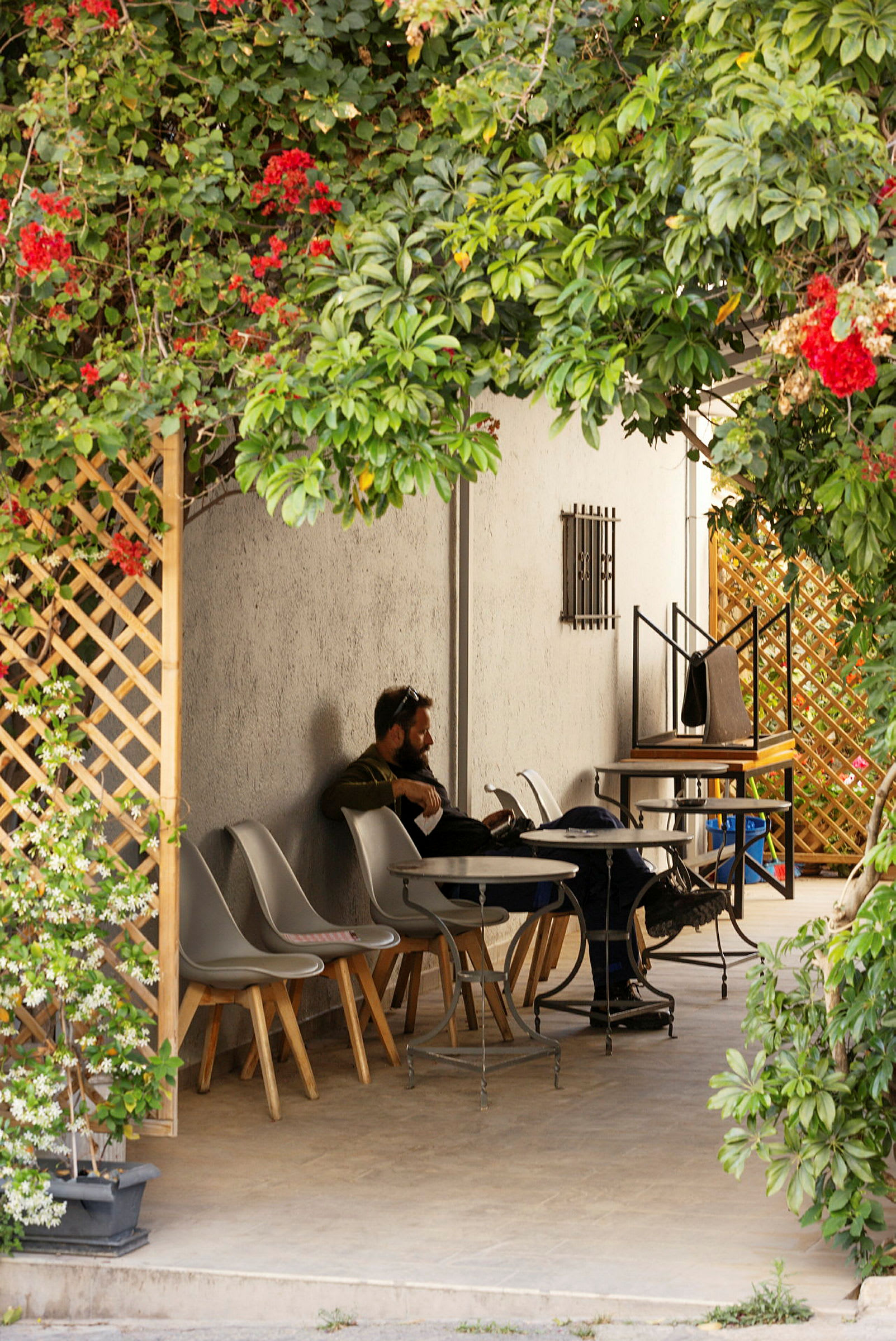 En lille terrasse med borde og stole omgivet af grønt. (AI-genereret tekst)