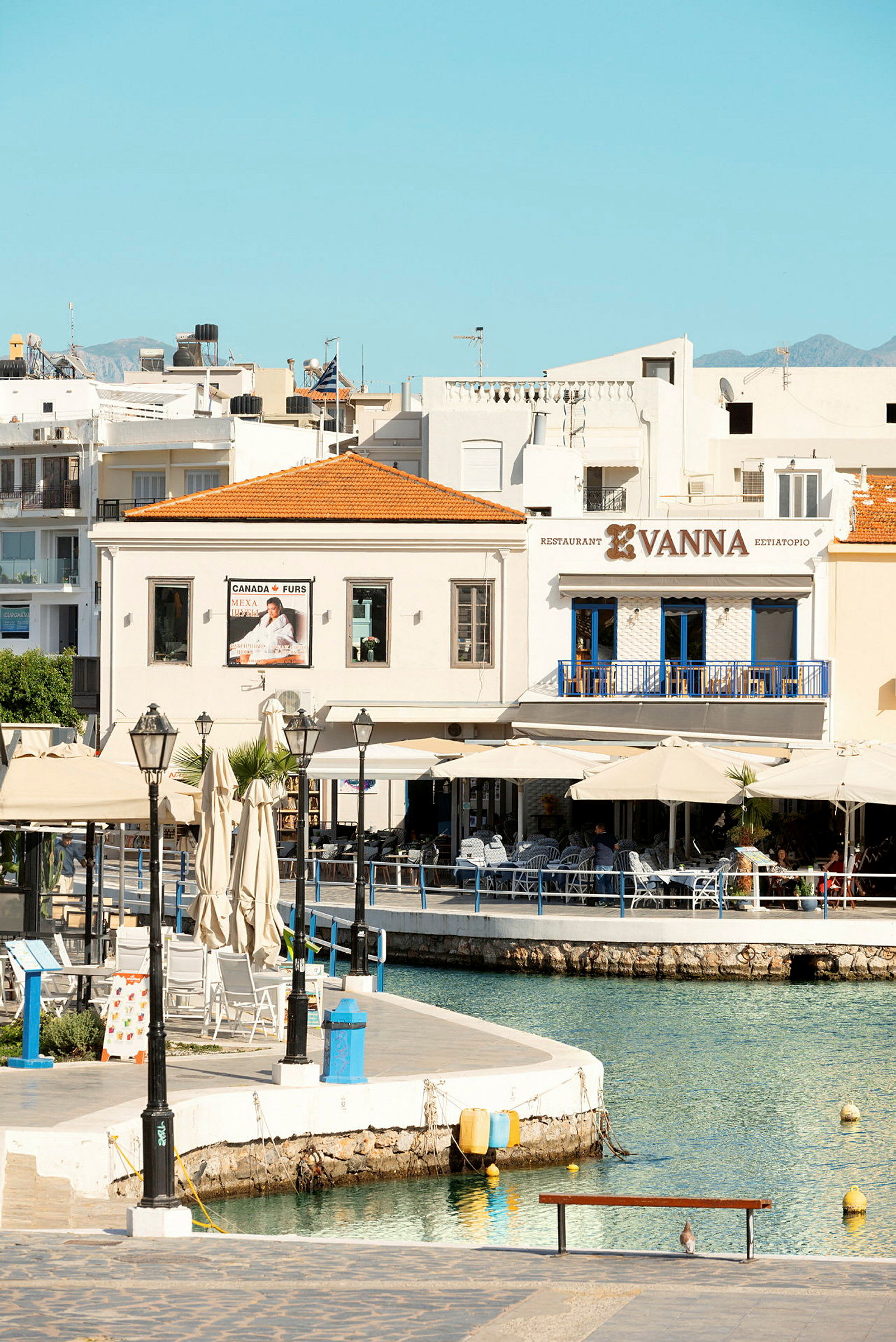 Udsigt over en lille havn med siddepladser og restaurant Vanna. (AI-genereret tekst)