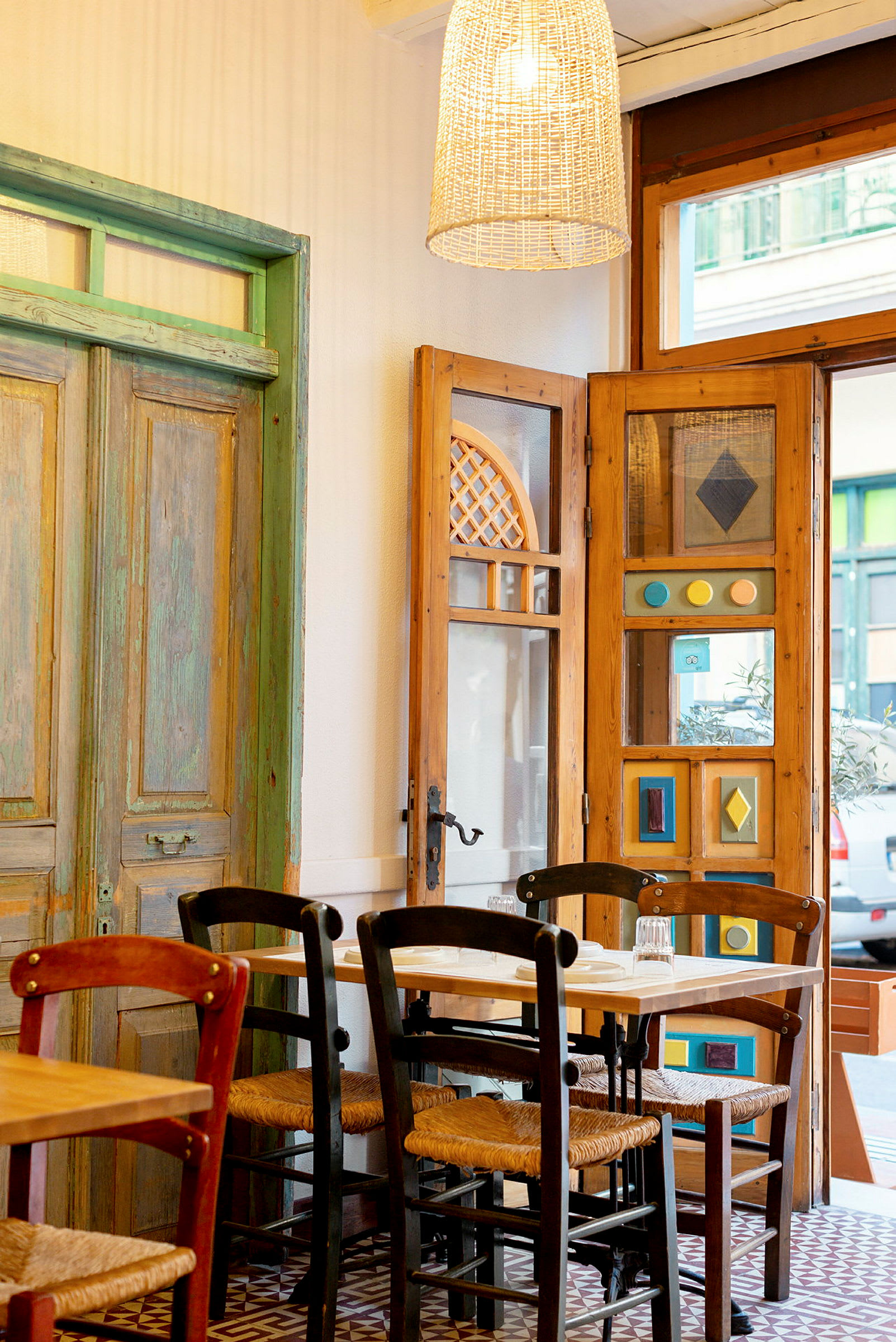 Interiør af en restaurant med træstole og et bord foran dekorative døre og vinduer. (AI-genereret tekst)