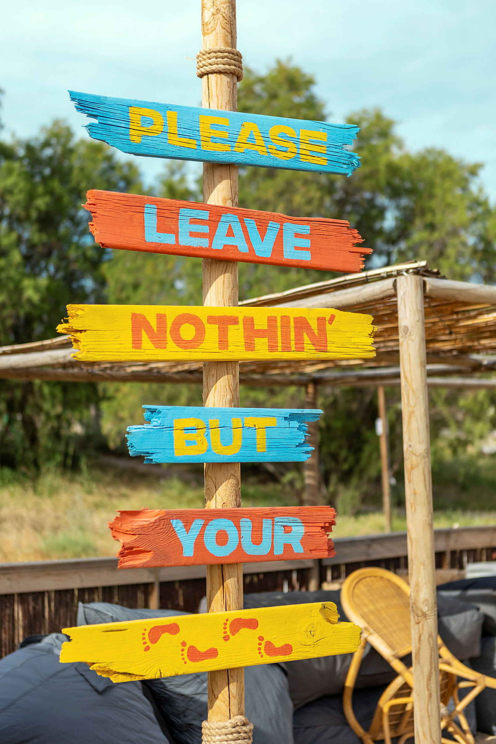 Skilt med teksten 'Please leave nothin’ but your', malet på farverige træplanker. (AI-genereret tekst)