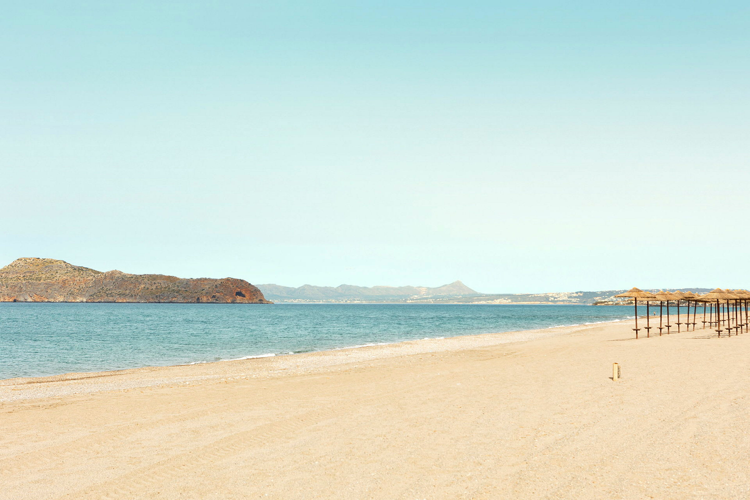 Strand med parasoller og hav i baggrunden. (AI-genereret tekst)