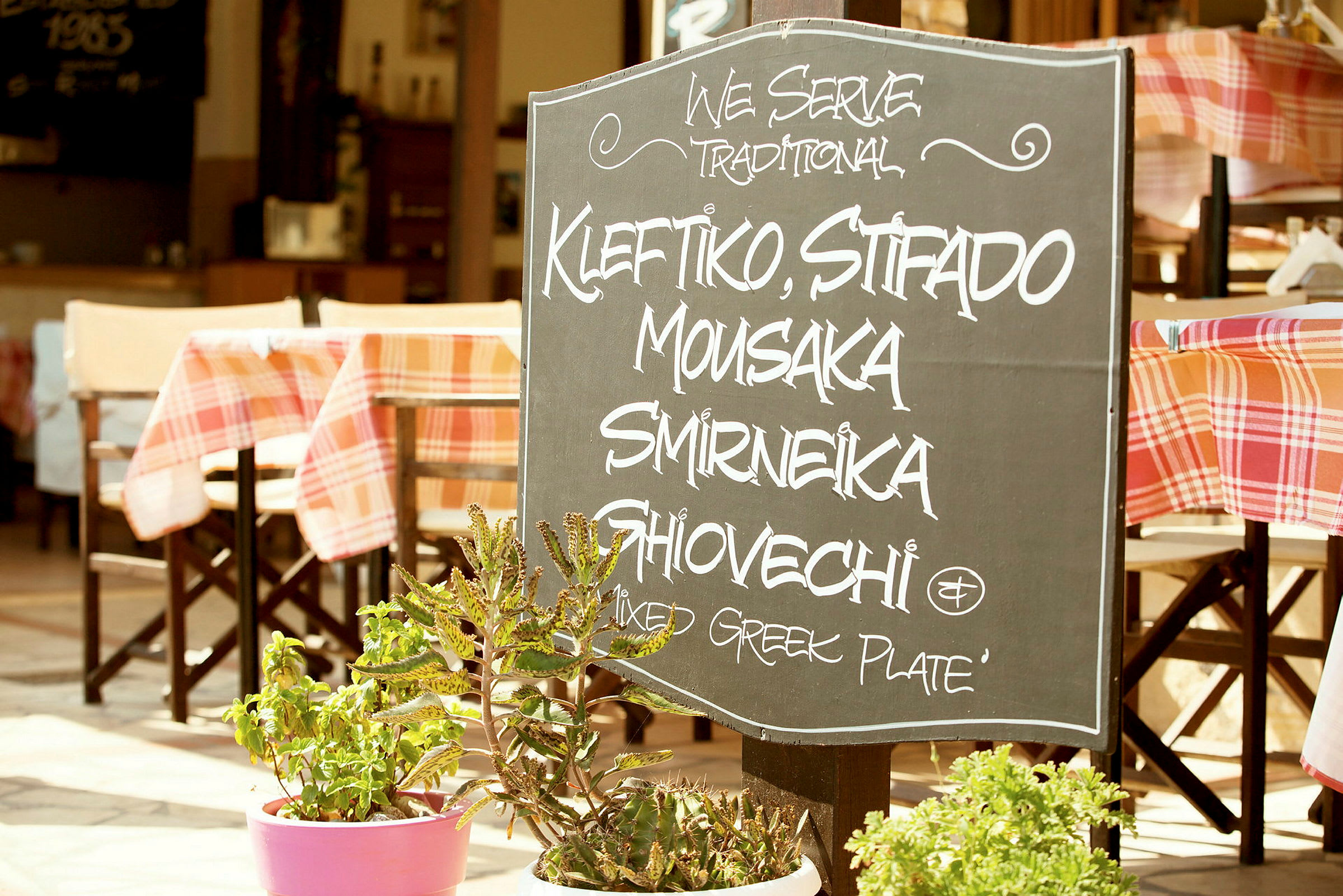 Et skilt uden for en restaurant med tekst, der oplister traditionelle græske retter. (AI-genereret tekst)