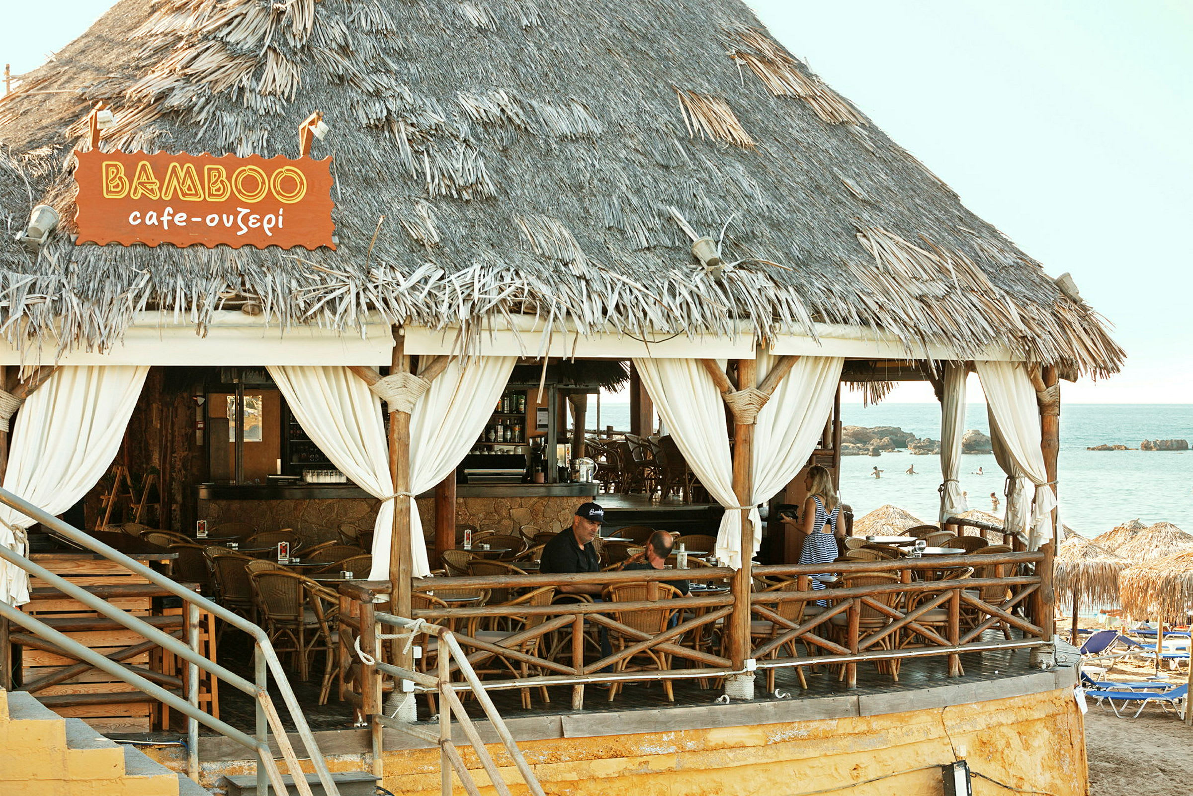 En strandbar med stråtag og træinteriør ved havet. (AI-genereret tekst)