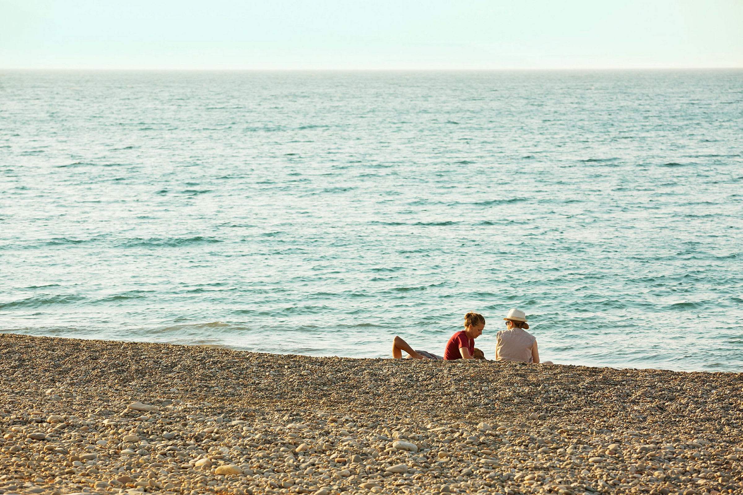To personer sidder på en stenstrand ved havet. (AI-genereret tekst)