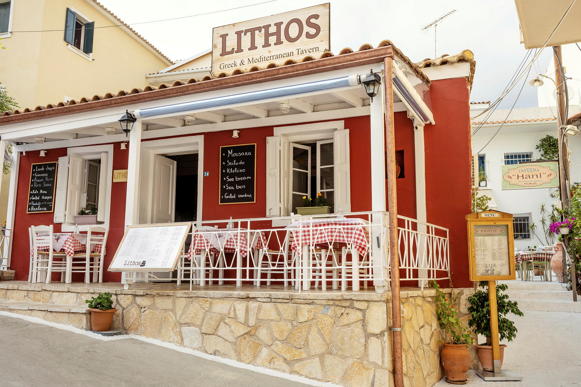 En græsk restaurant ved navn Lithos, rød facade og hvide møbler. (AI-genereret tekst)