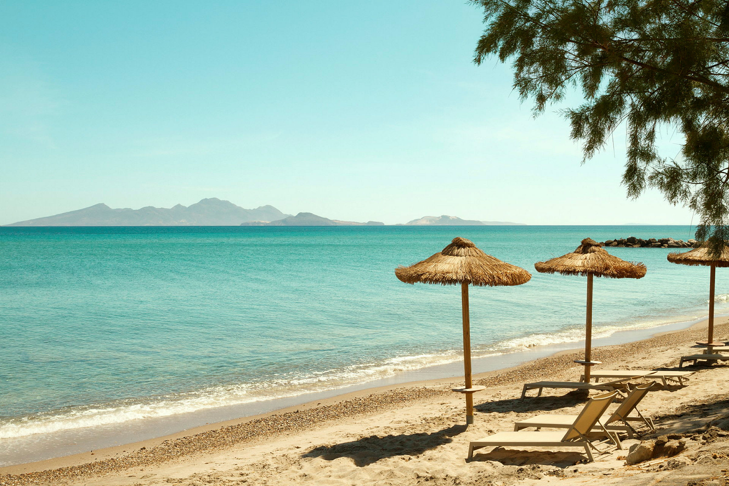 Strand med parasoller og liggestole ved havet. (AI-genereret tekst)