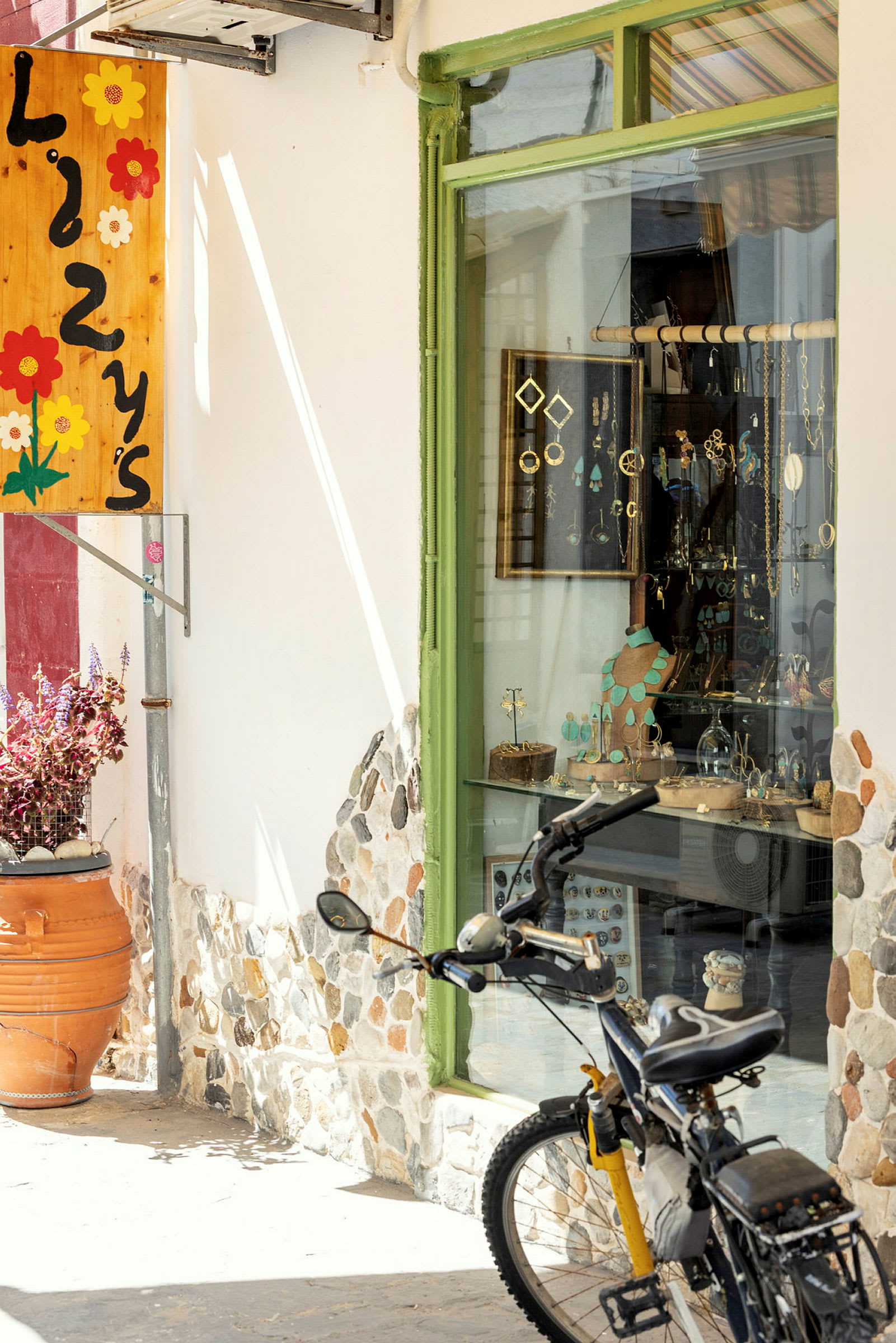 Billedet viser en cykel parkeret foran en butik med et grønt butiksvindue og dekorative genstande. (AI-genereret tekst)